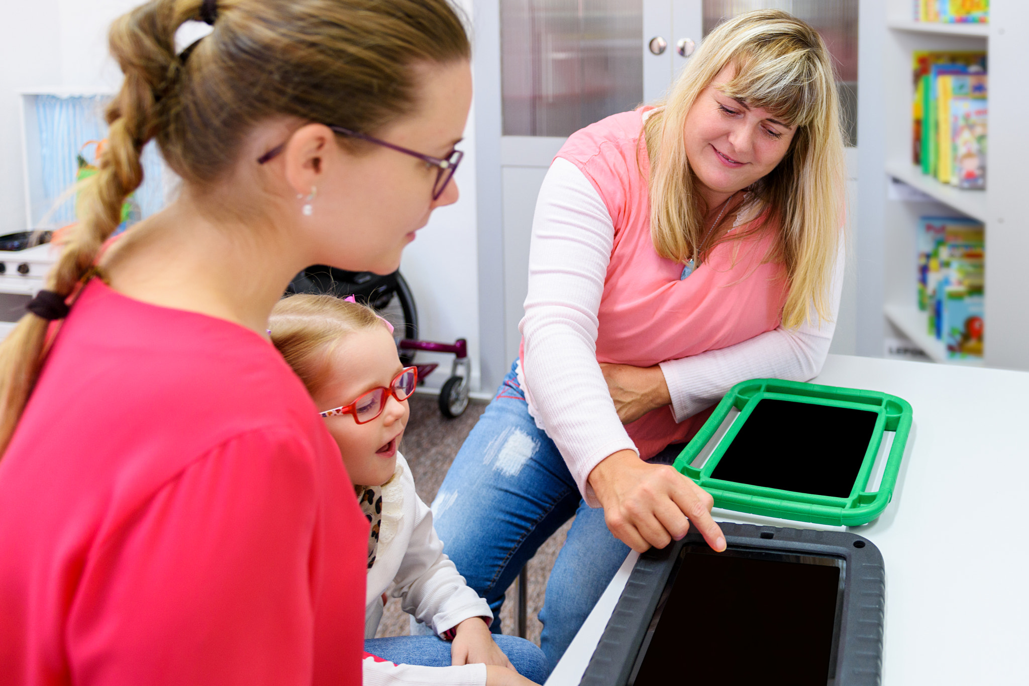 Non-verbal girl living with cerebral palsy, learning to use digital tablet device to communicate.