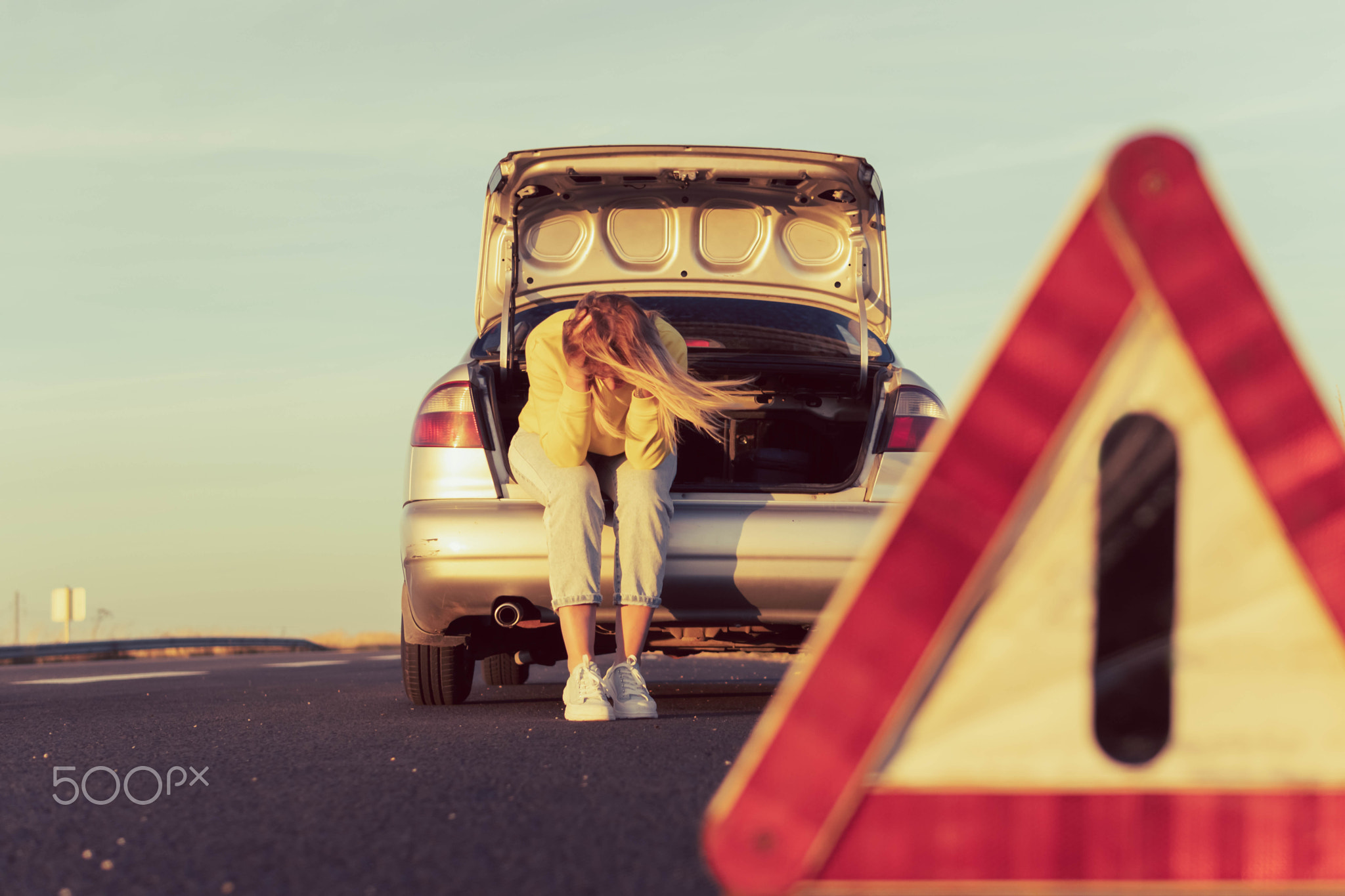 a girl with blond hair in casual clothes sits in the trunk holding her