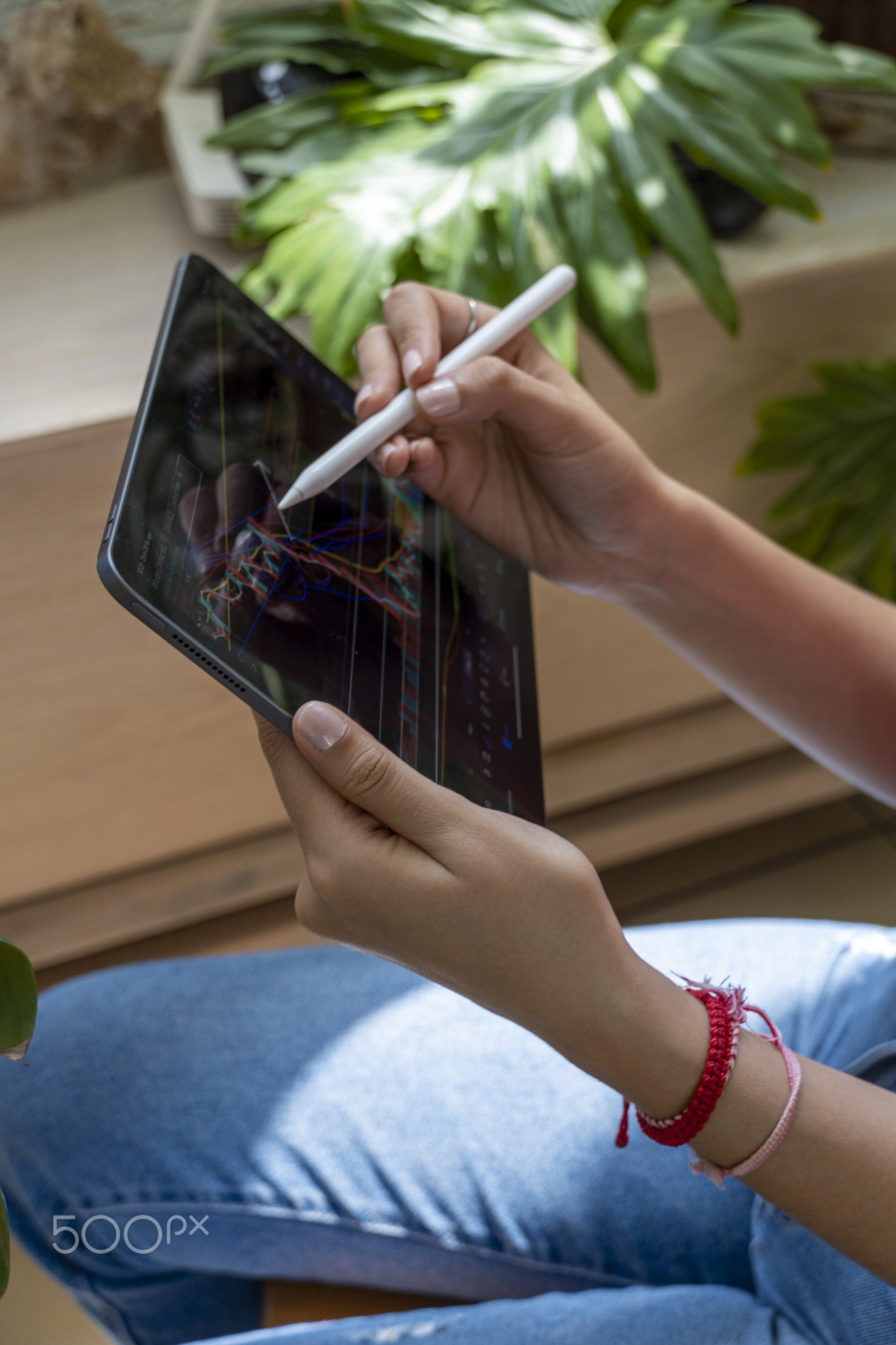 young woman, watching the stock market on her tablet, while drawing on