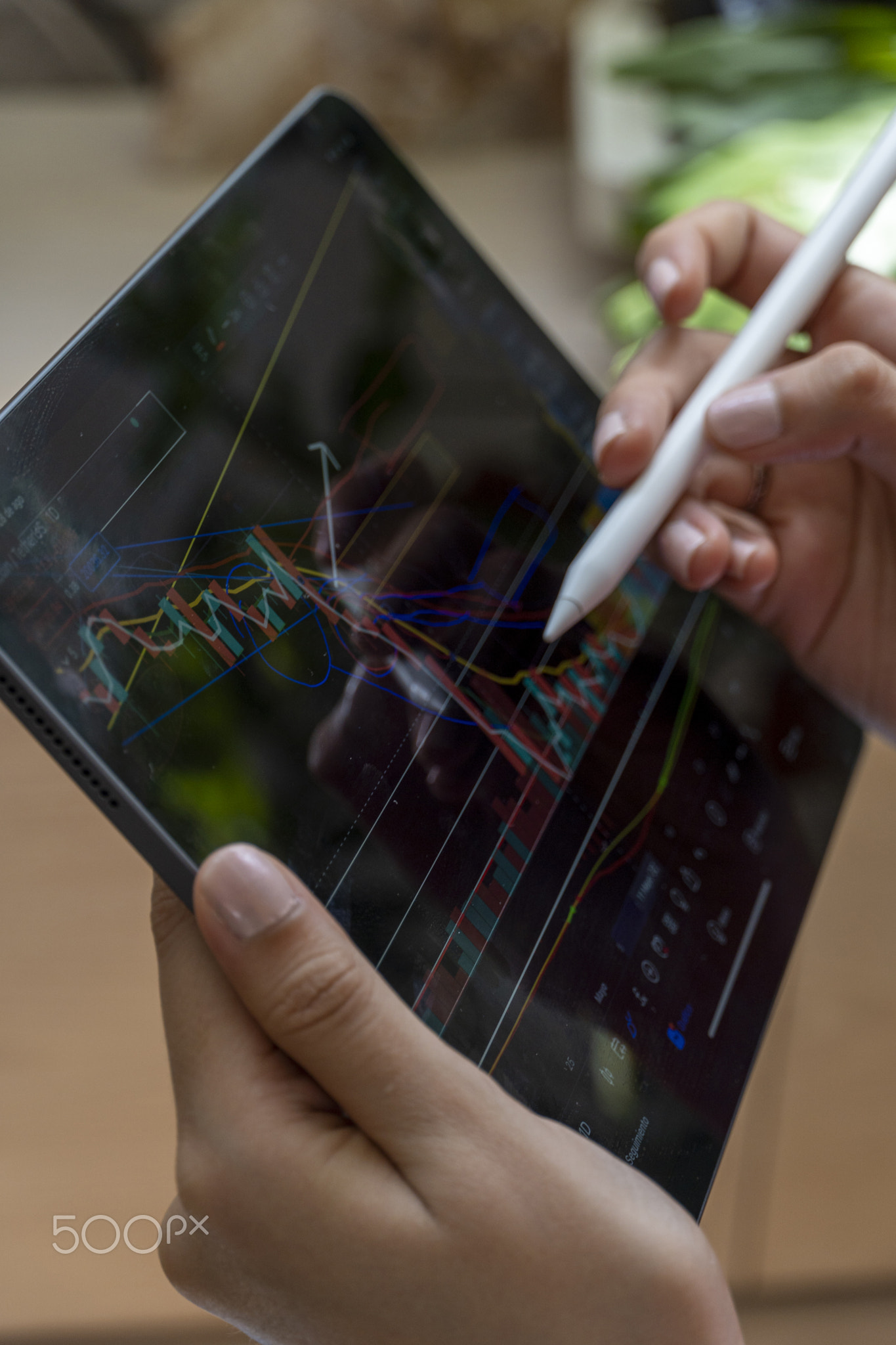 young woman, watching the stock market on her tablet, while drawing on