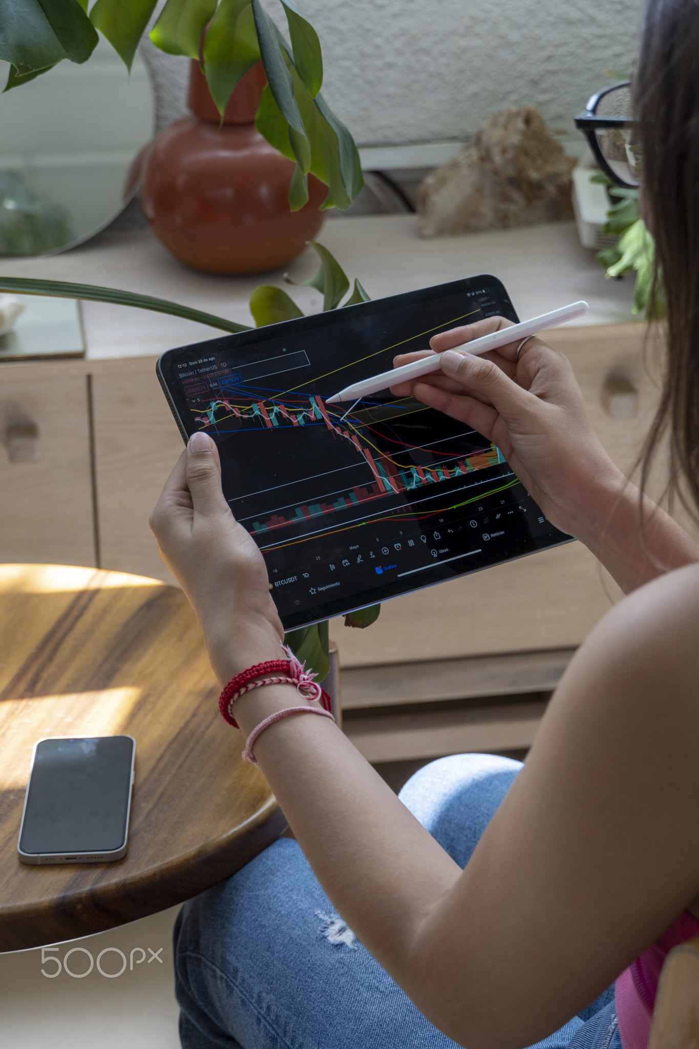 young woman, watching the stock market on her tablet, while drawing on