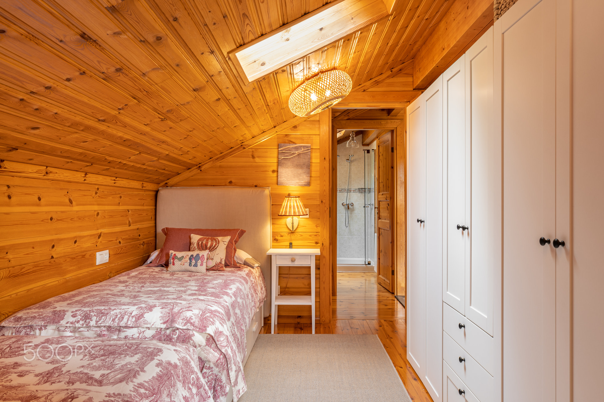Narrow bedroom with beds and white wardrobe in a modern cottage with