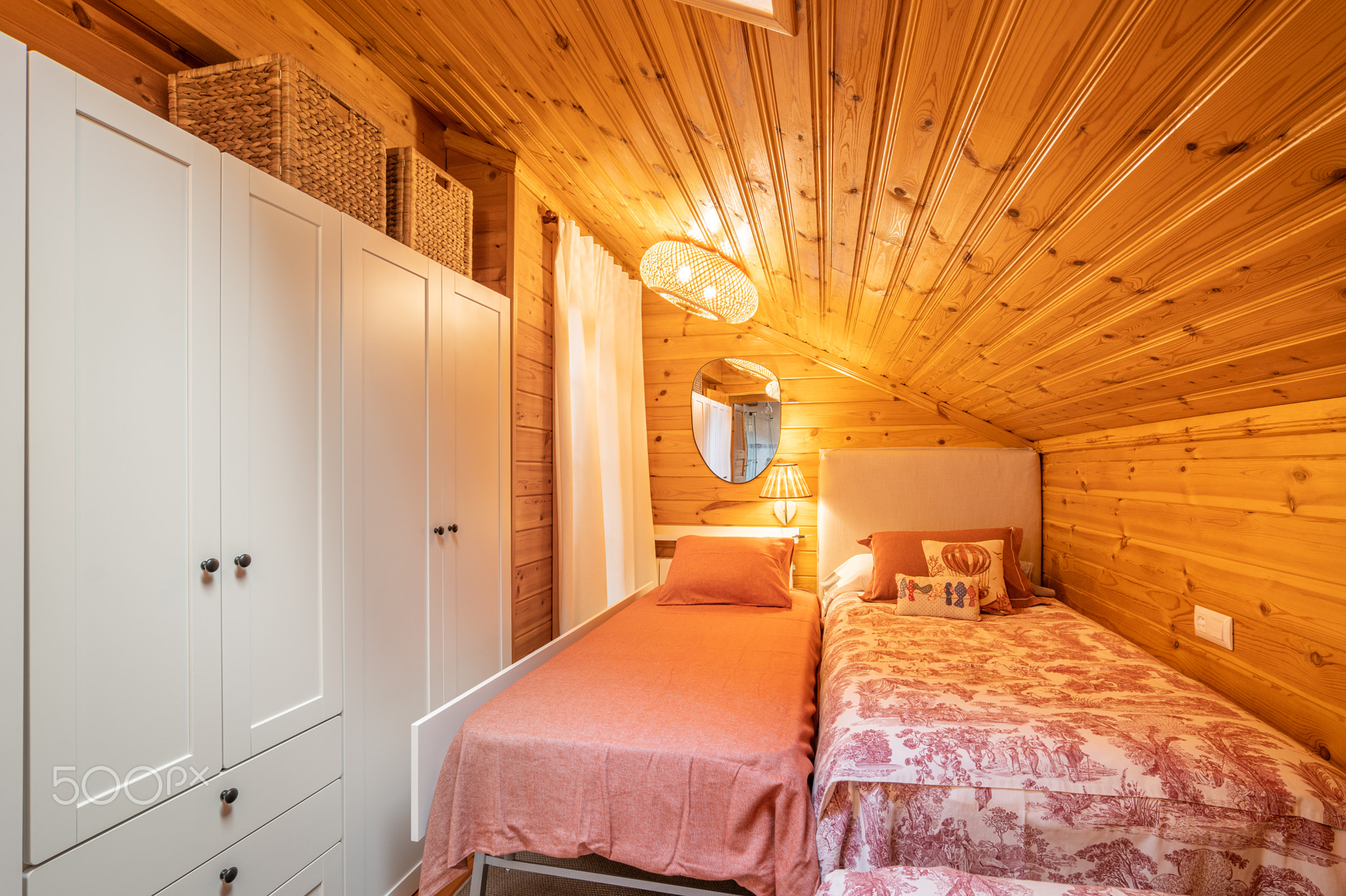 Small bedroom with two beds and white wardrobe in a modern cottage