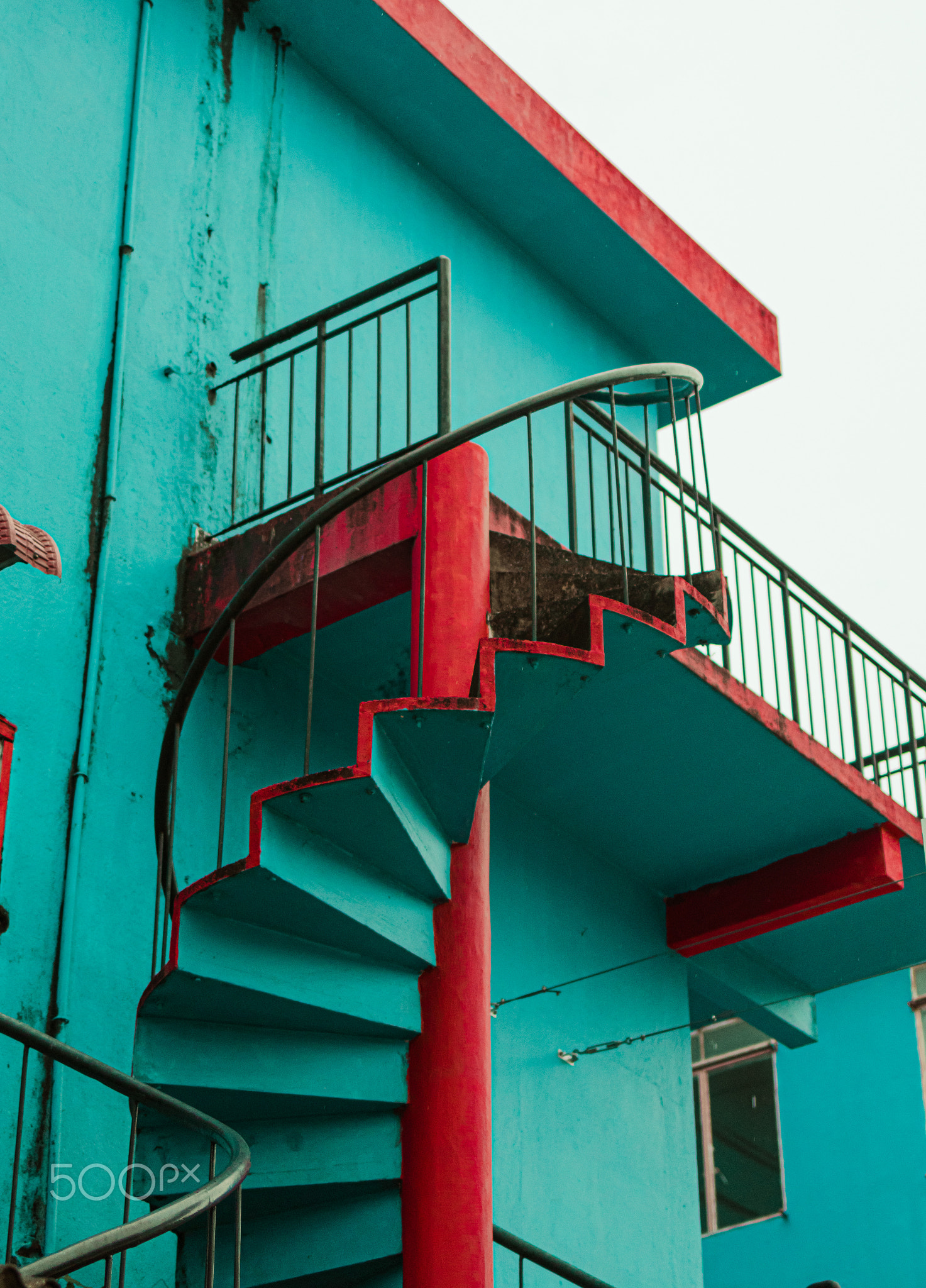 Beautiful spiral staircase on the side of a green and red color building in Perlis, Malaysia.
