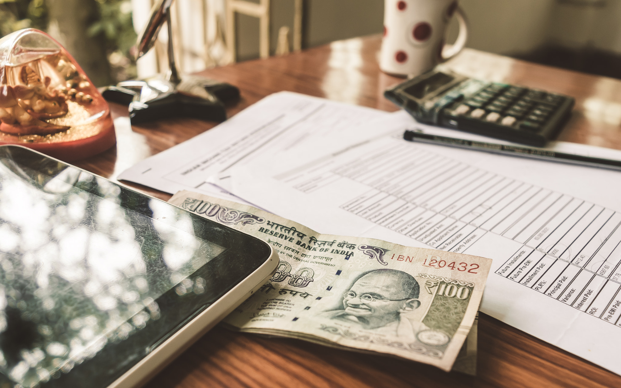 Indian Currency is on the table next to a pen, calculator, currency