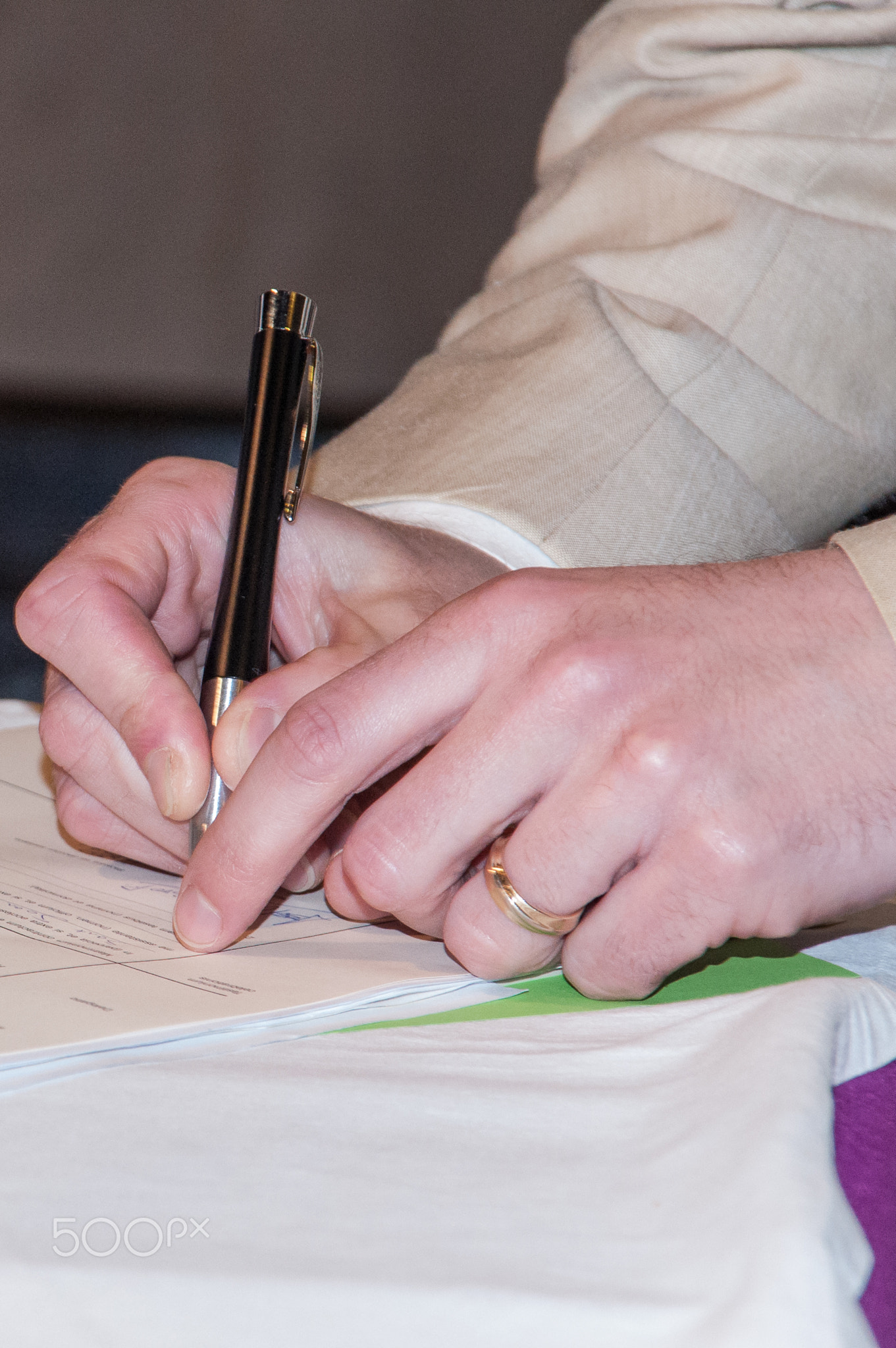 Close up young businessman standing near table with pen in hands