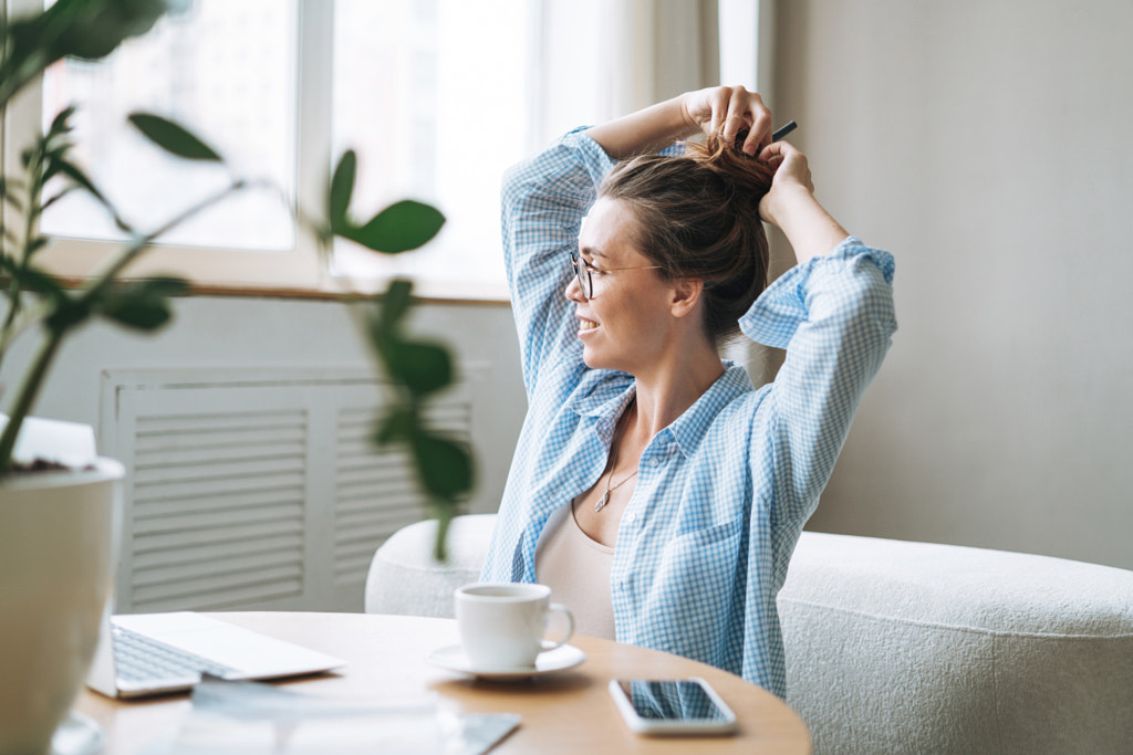 Young smiling woman in blue shirt using laptop drinking tea in room by Galina Zhigalova on 500px.com