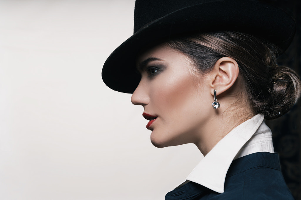 Close-up of fashionable young woman wearing hat against gray background by Vlad Shutov on 500px.com