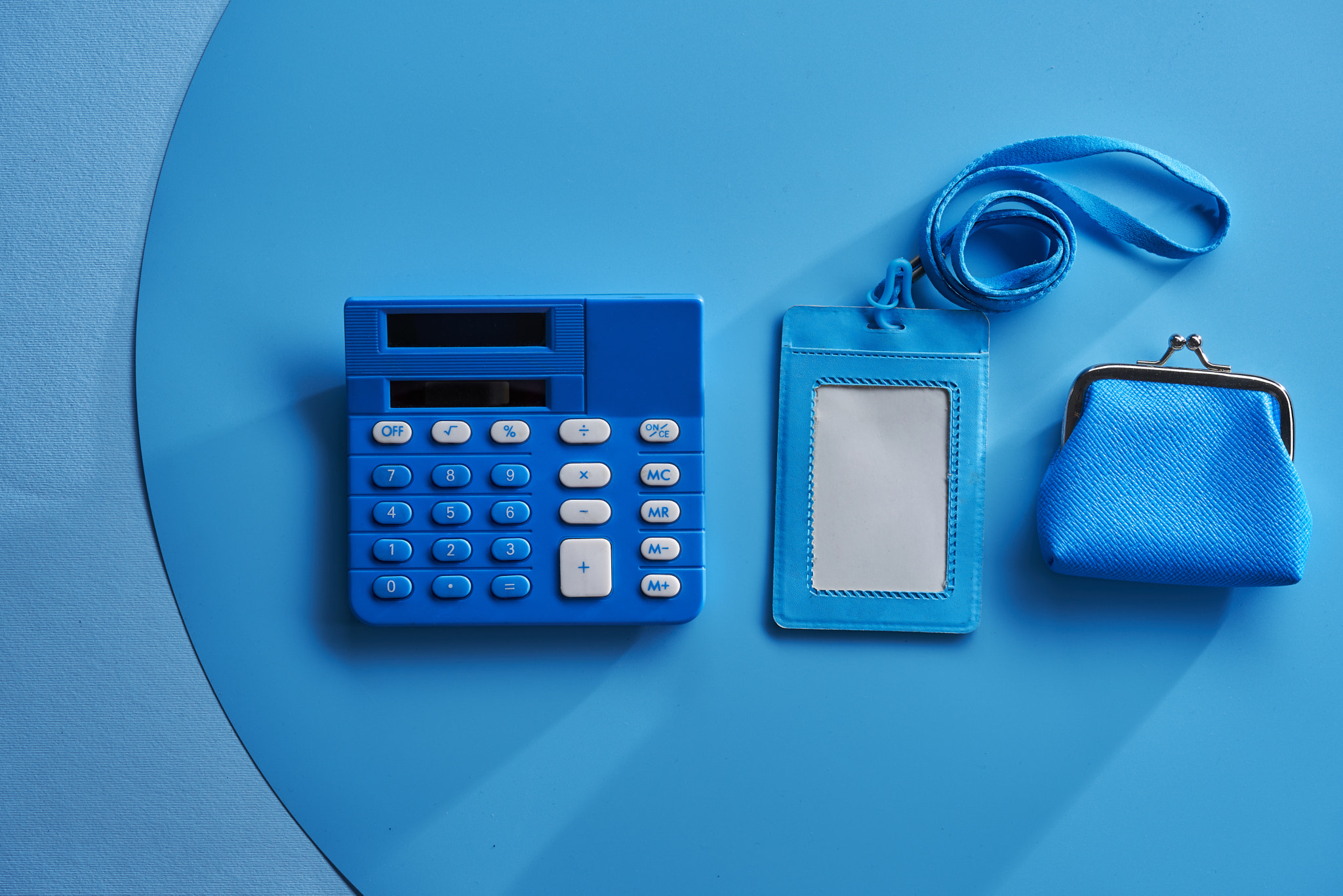 blank name tag holder calculator and coin purse against blue background