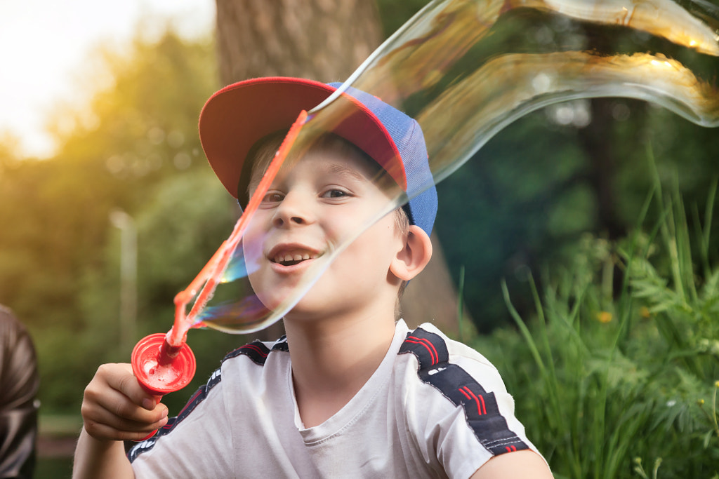 Son with mom having fun on green lawn with soap bubbles in summer public park, together in sunny day by Alexander Golubev on 500px.com