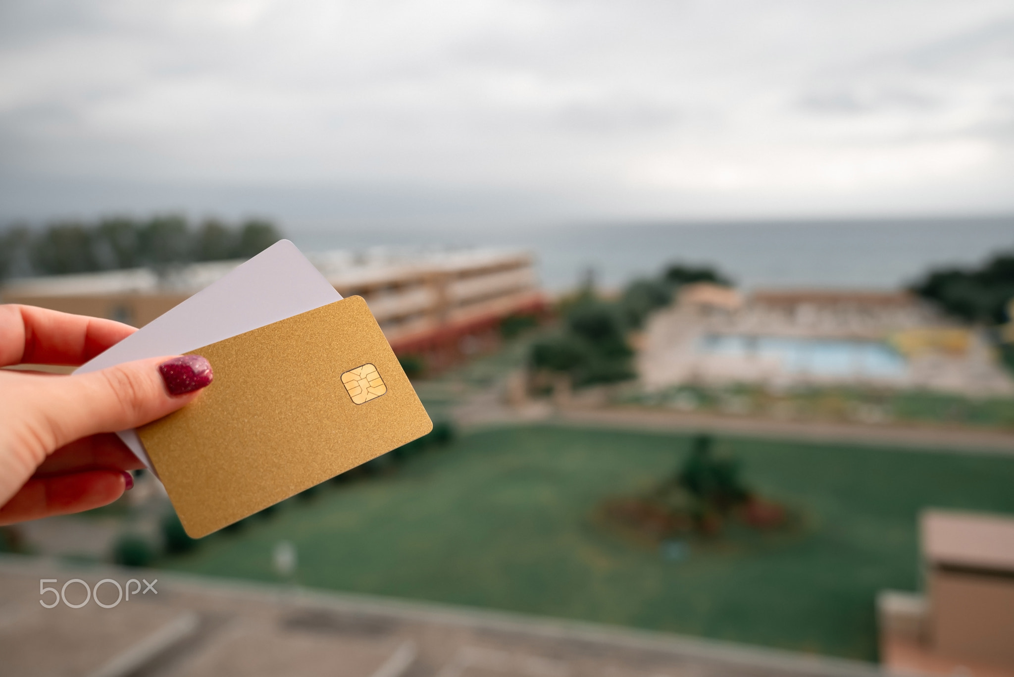 Golden and White Bank Card In Woman Hand On Background Of Hotel