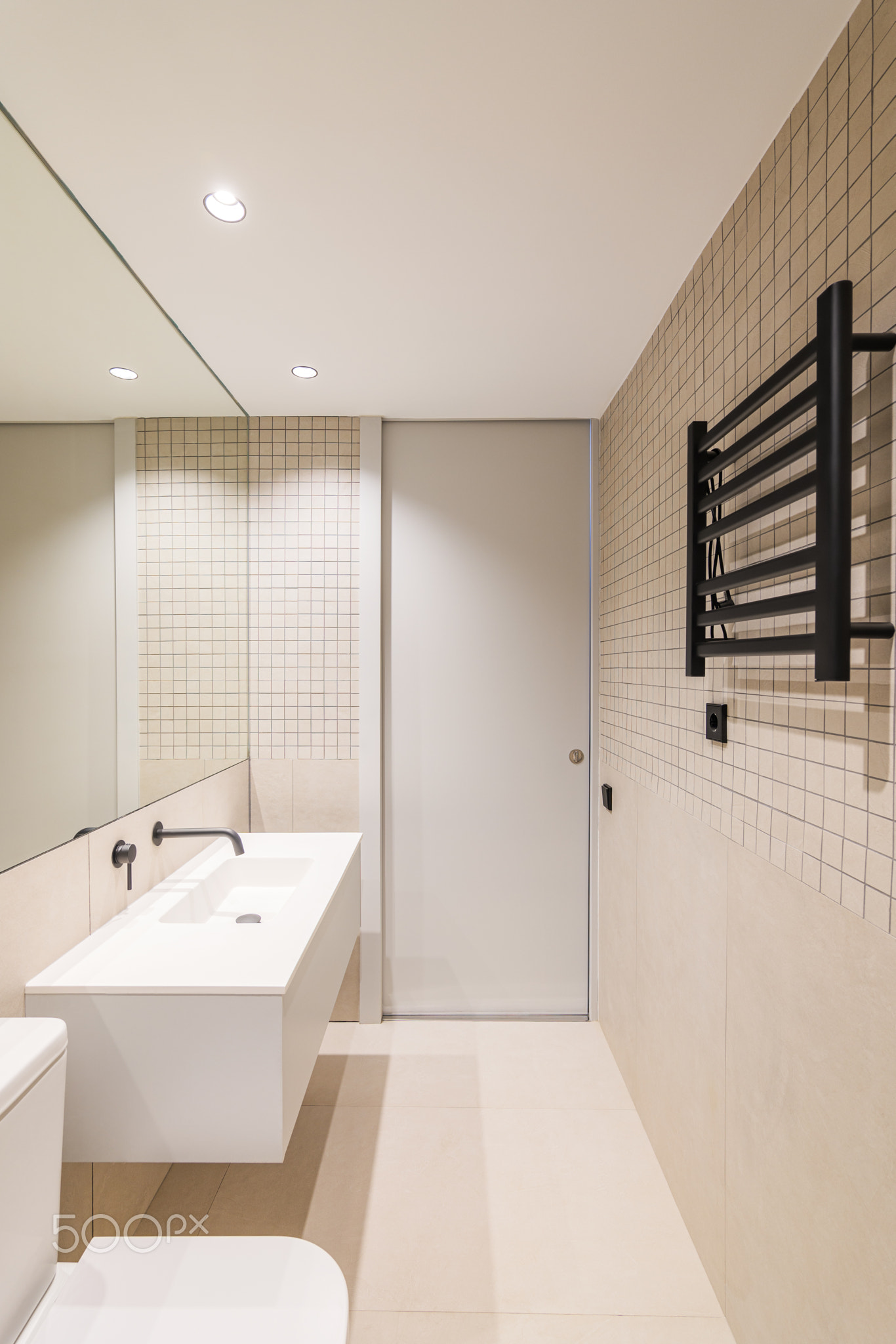Vertical view of interior of modern bathroom with beige tiles, black
