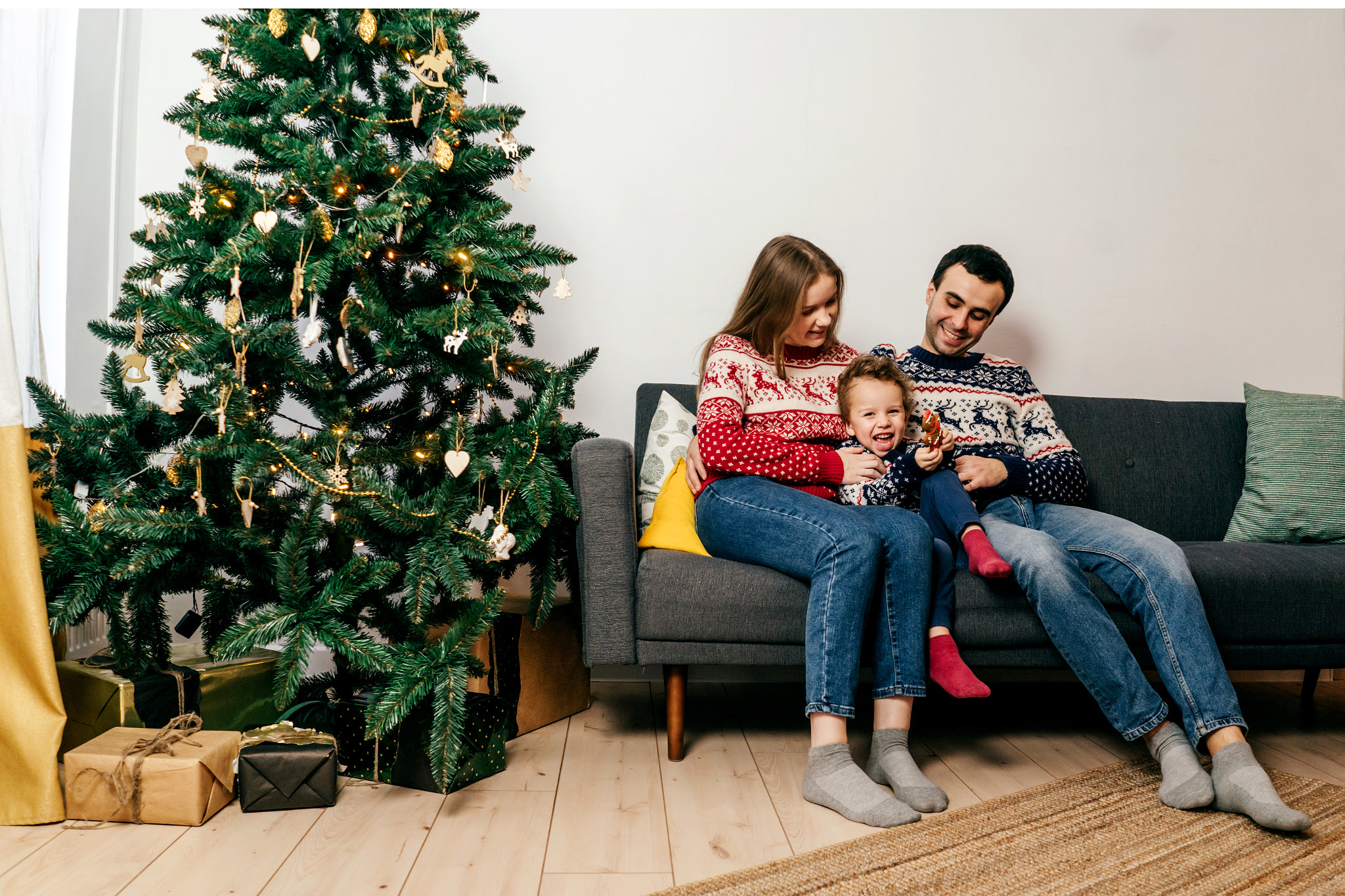 Happy family sitting on sofa near Christmas tree.