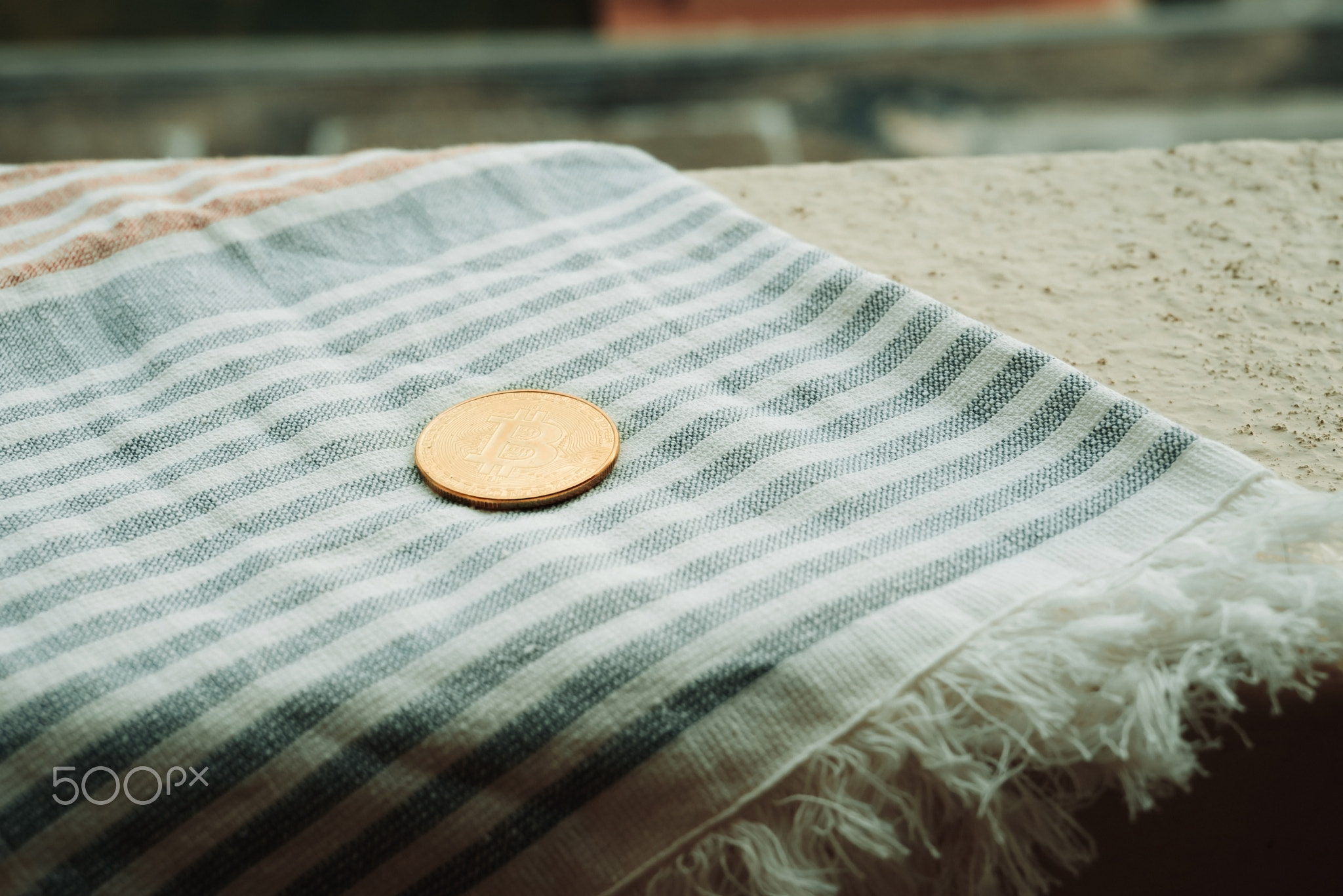 Bitcoin Coin Lies On Beach Towel On Background Of Hotel Swimming Pool
