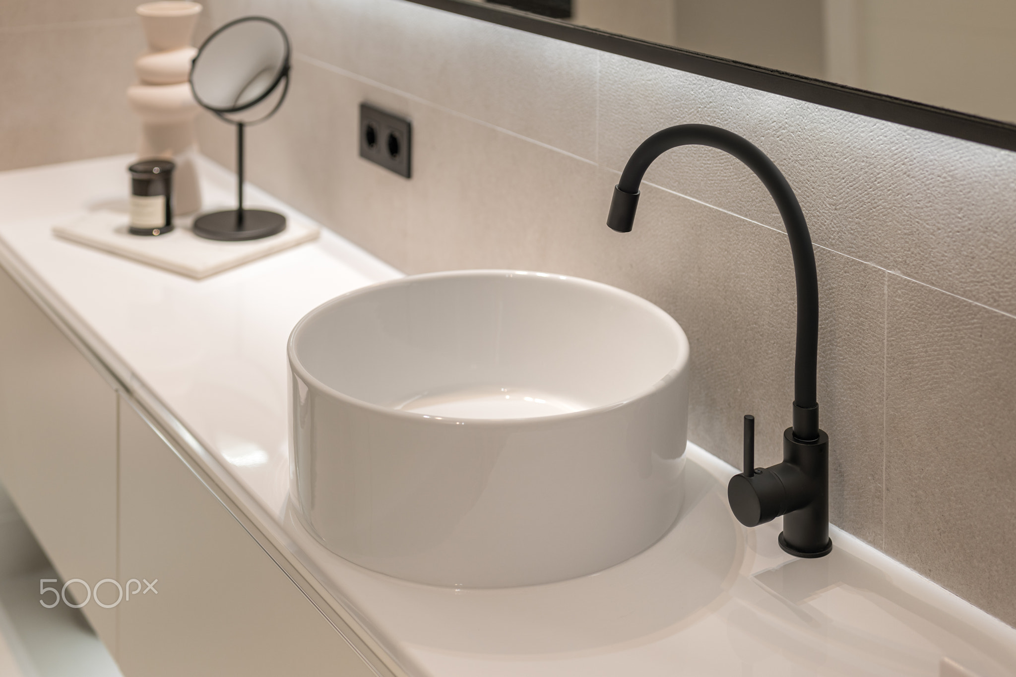 Close-up of modern black faucet and white round sink on pedestal