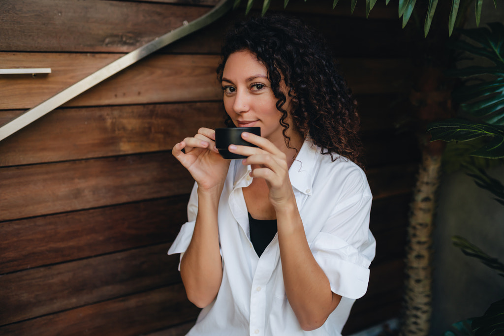 Portrait d'une jeune femme souriante buvant du café assis sur le porche par Natalie Zotova sur 500px.com