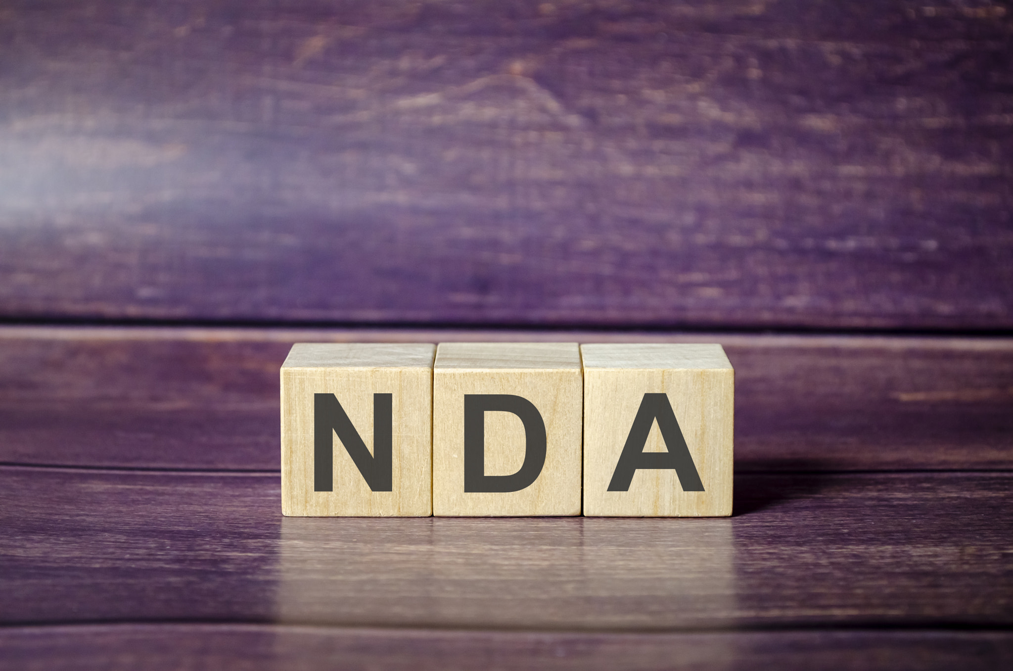 word NDA on wooden blocks and brown background