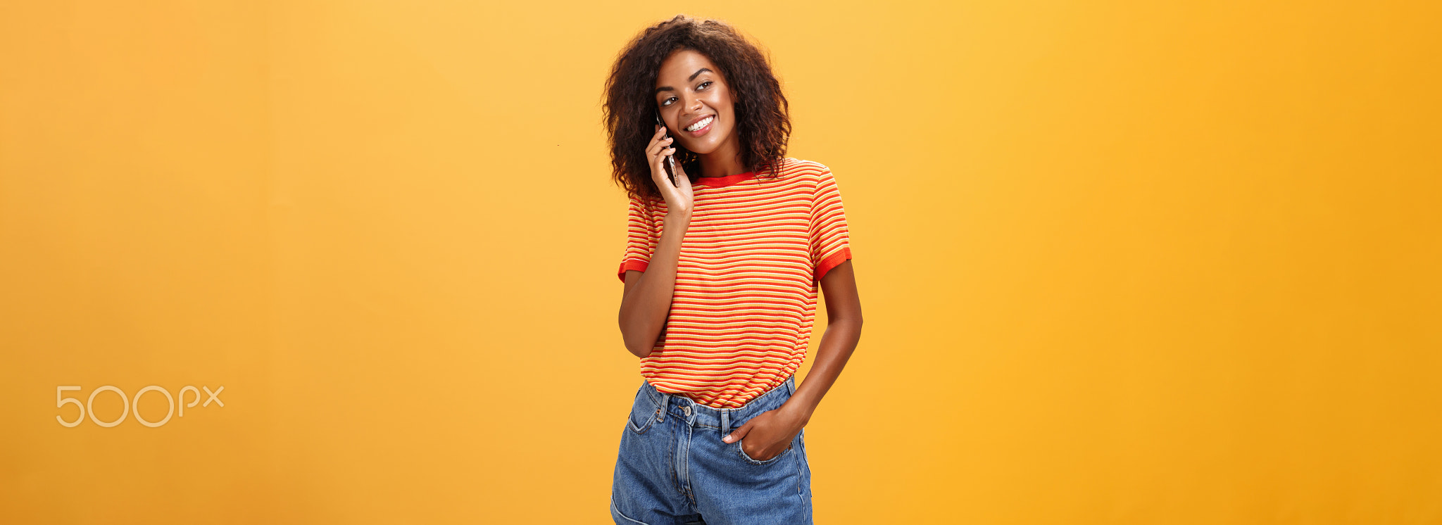 Stylish dark-skinned girl making casual phone call to friend telling