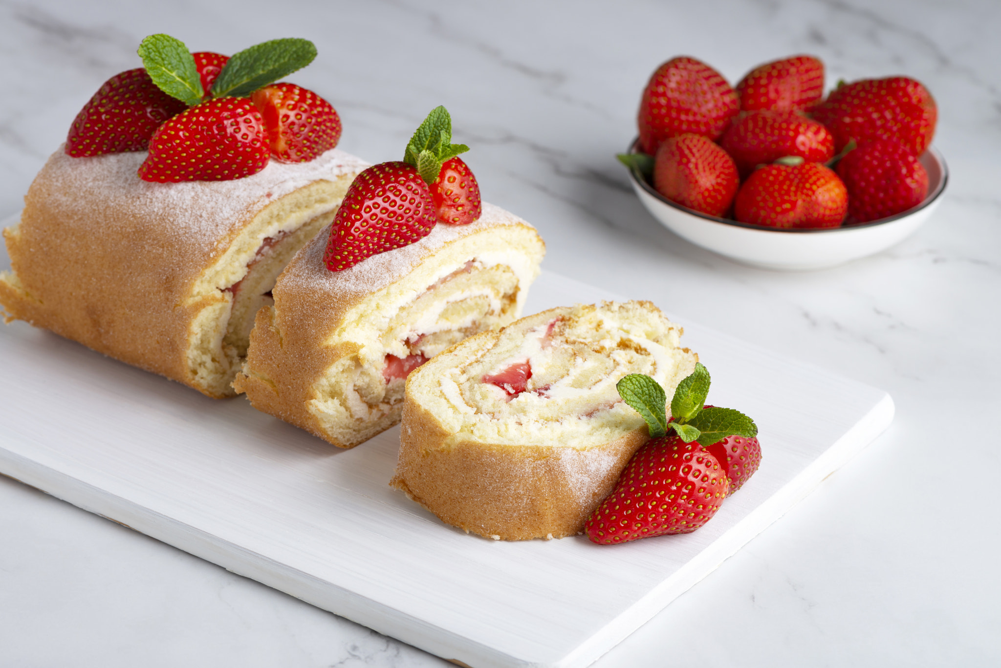 Sweet roll stuffed with strawberry and cream decorated with strawberries, powdered sugar