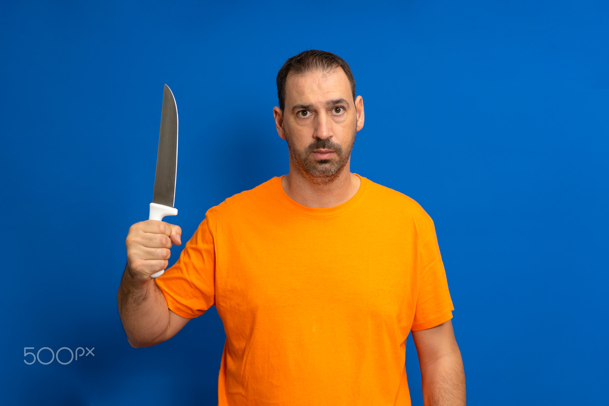 Caucasian man with beard holding kitchen knife with threatening and
