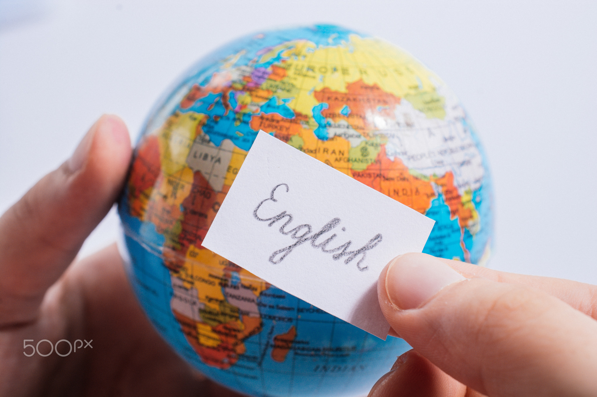 Hand holding notepaper with English wording on globe