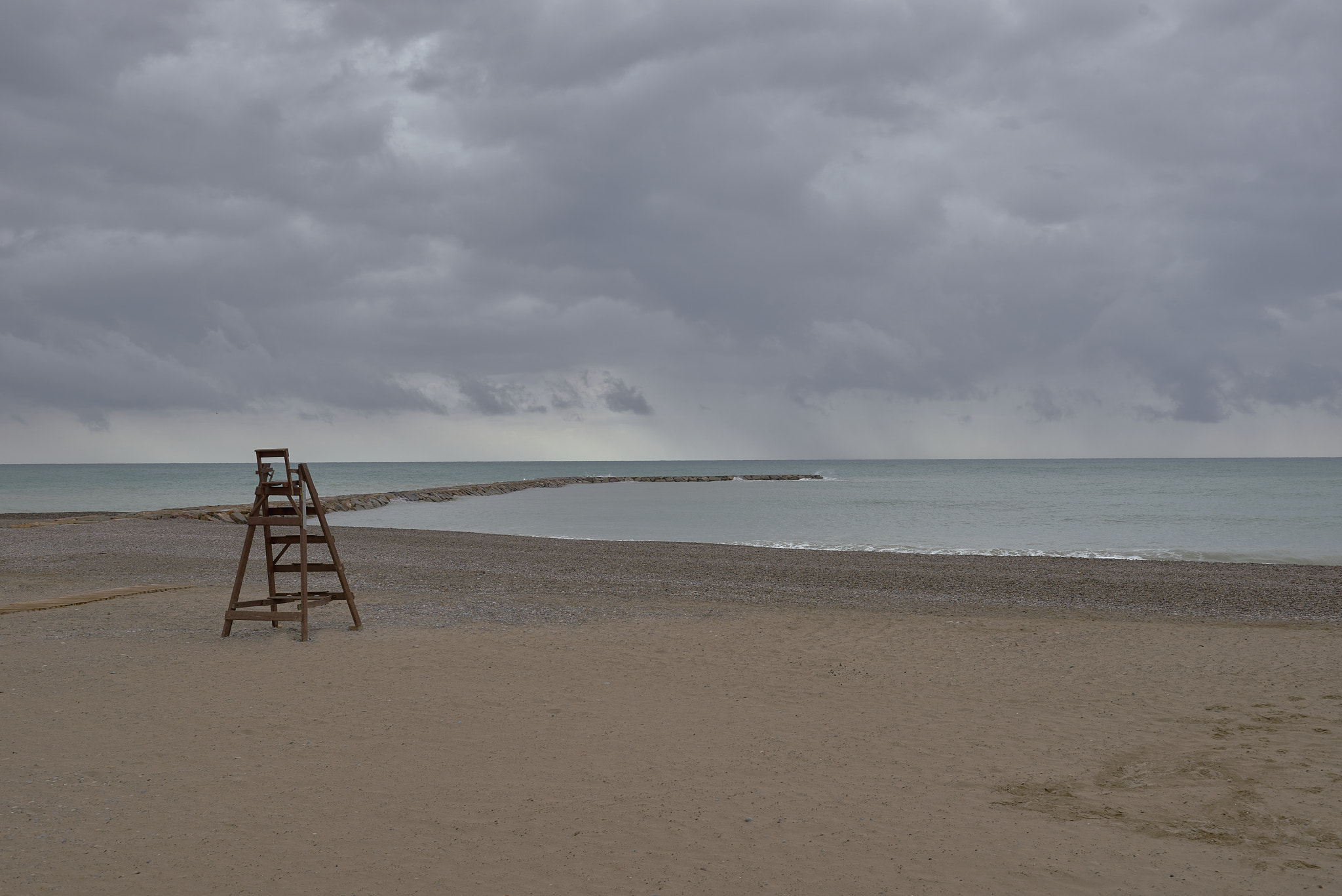 Wooden lifeguard chair on lonely beach. Cloudy sky