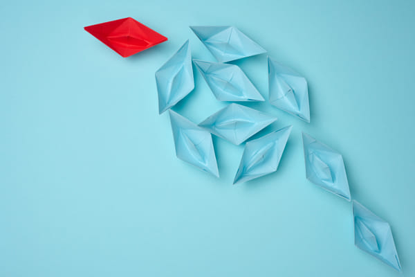 Group of blue paper boats heading in one direction and one red one heading  by Natalia Danko on 500px.com