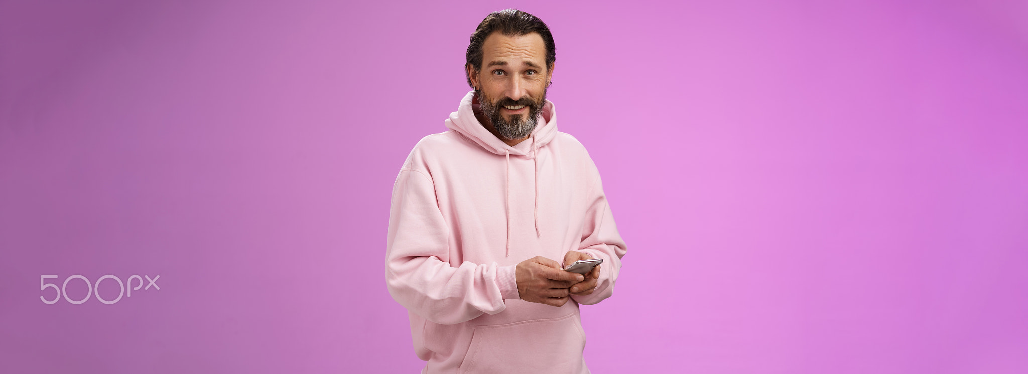 Stylish handsome adult bearded guy 40s in trendy pink hoodie holding