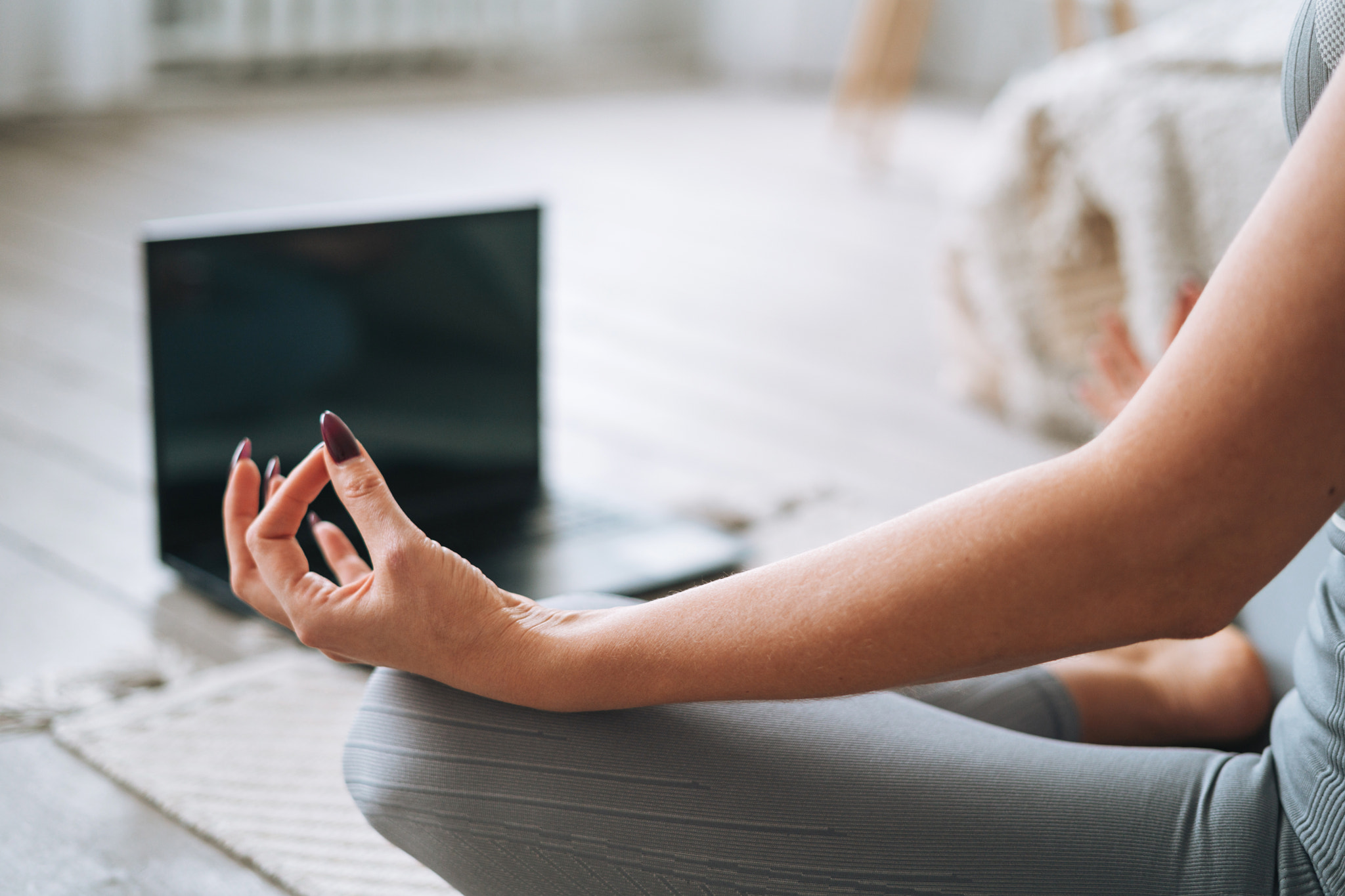 Young woman in sportswear practice yoga with laptop online in bedroom at home