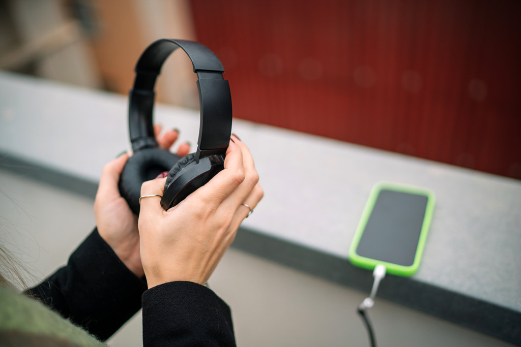 Cropped hand of woman holding headphones at table by Olha Dobosh on 500px.com