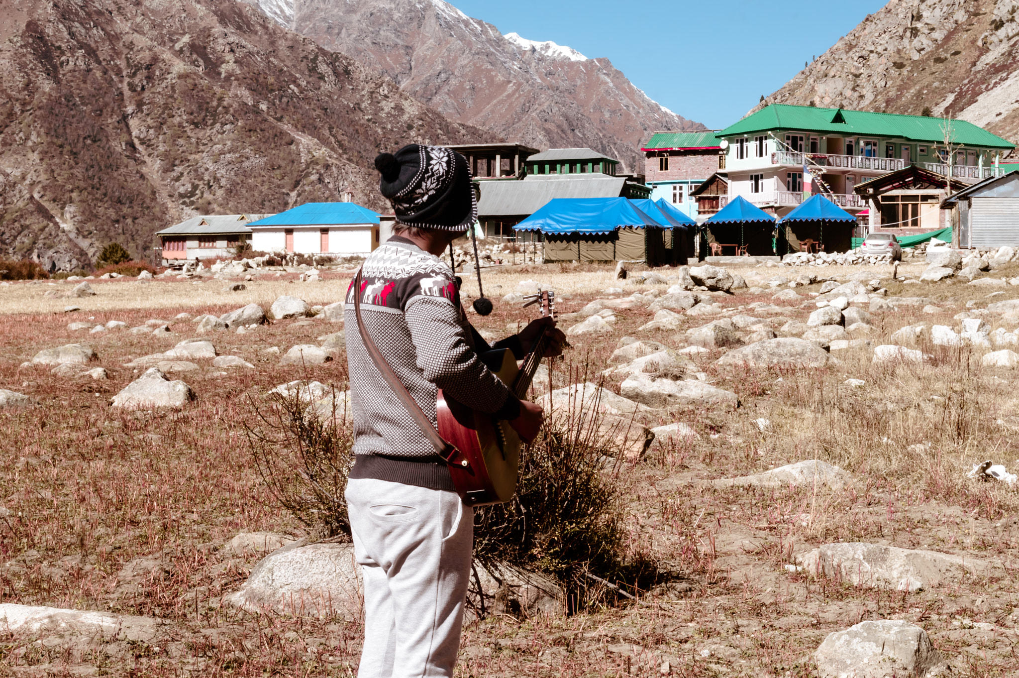 A solo traveler musician playing guitar in Himalayan mountain valley