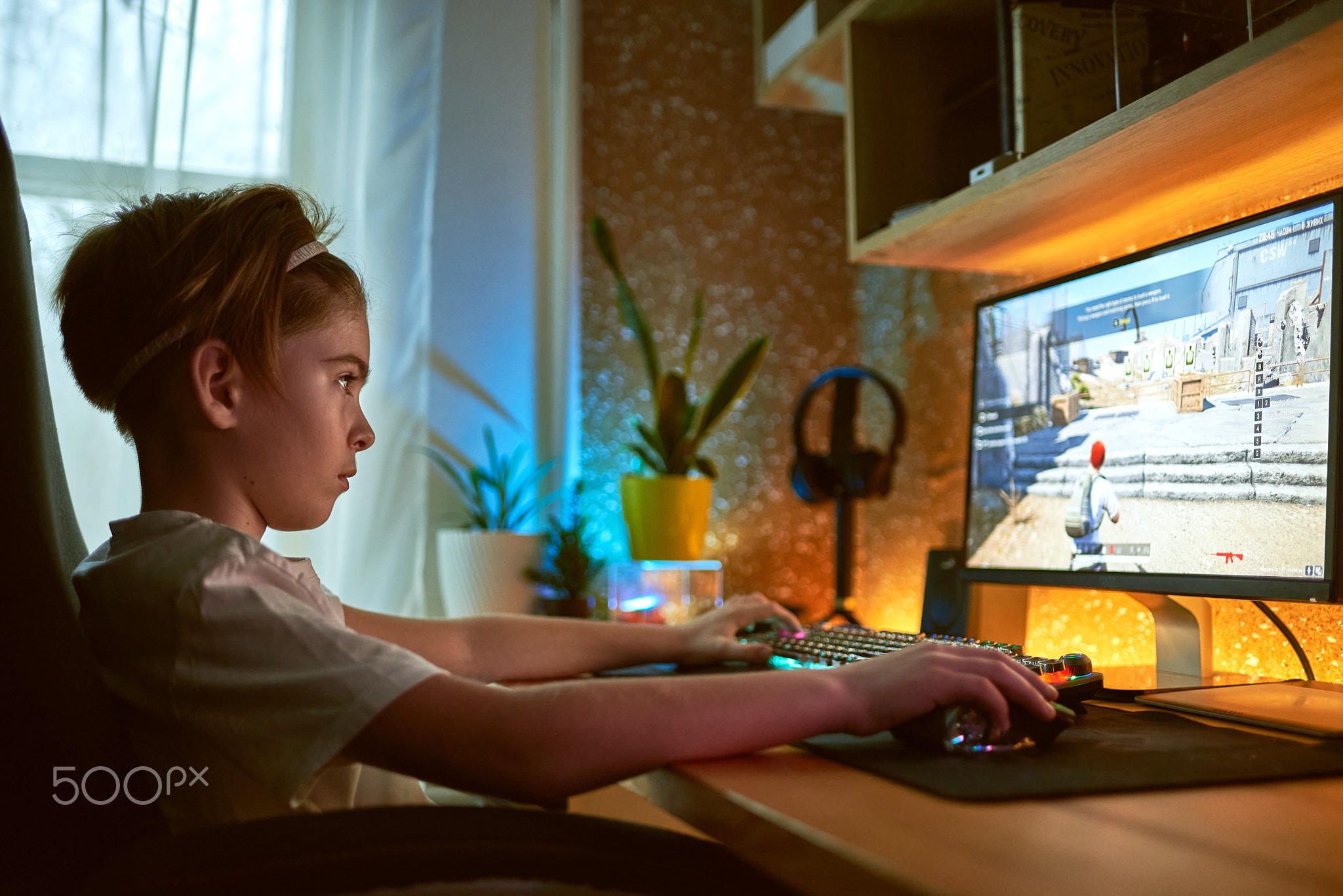 Image of immersed teenage gamer boy playing video games on computer in