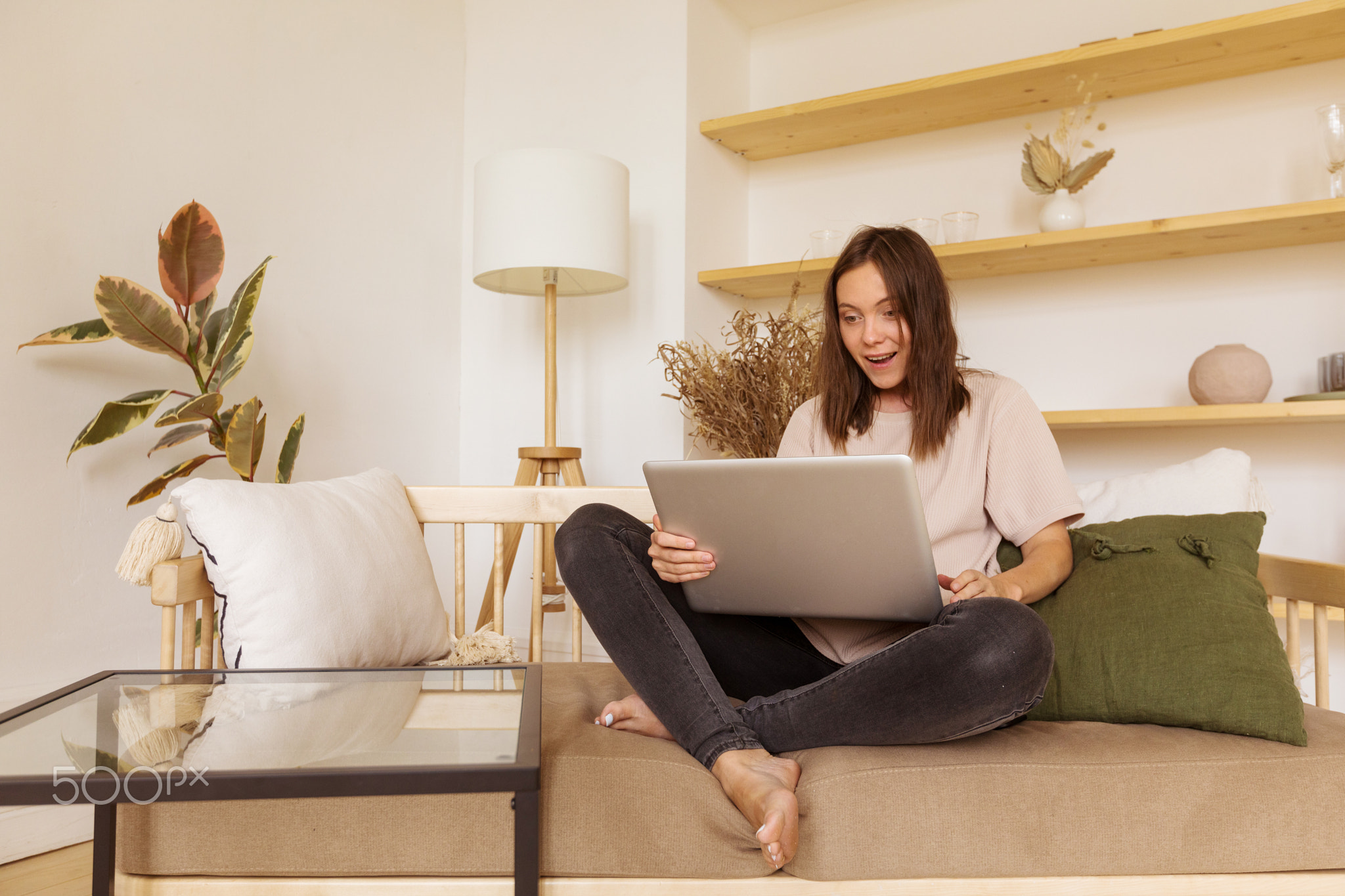 Excited woman using laptop on sofa