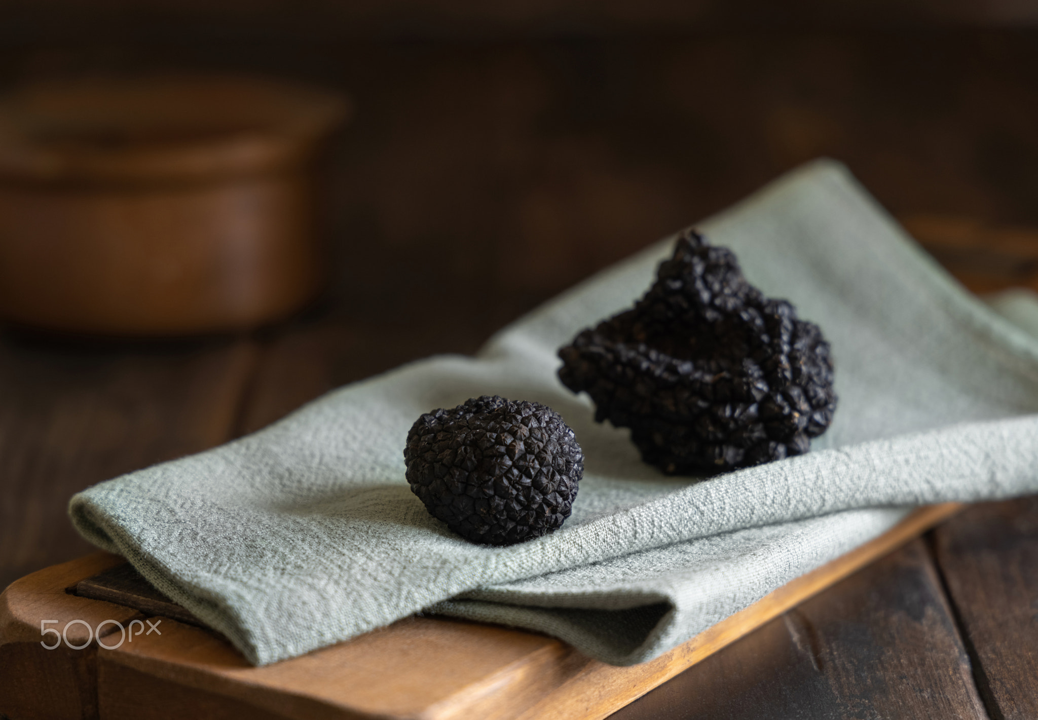 Whole black truffles mushroom on wooden board on green napkin, close up