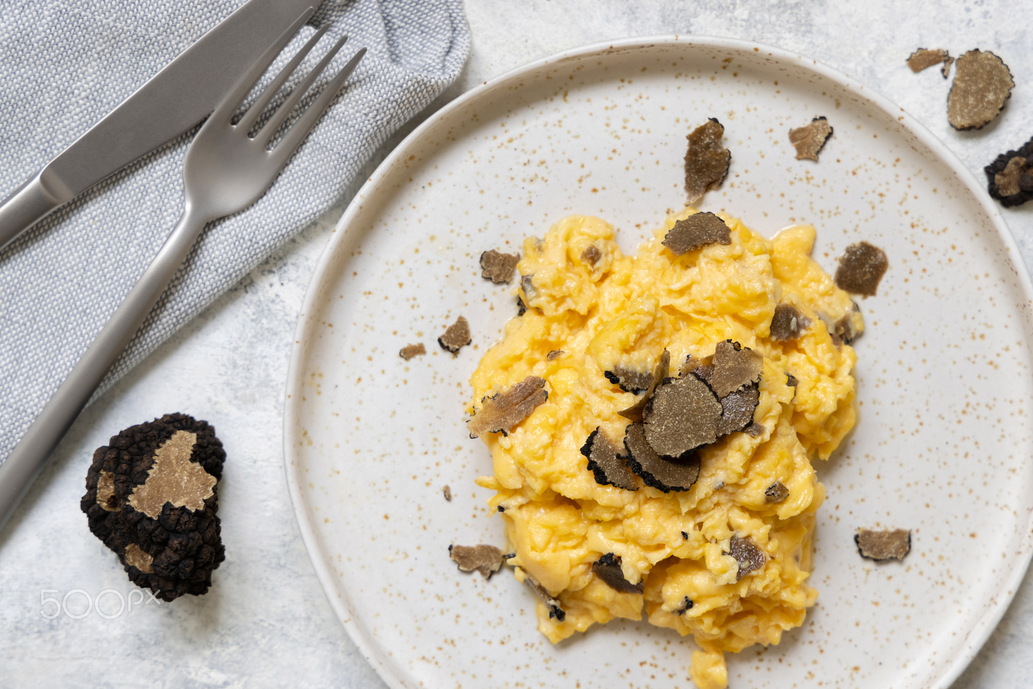 Scrambled eggs with fresh black truffles from Italy served in a plate top view, gourmet breakfast