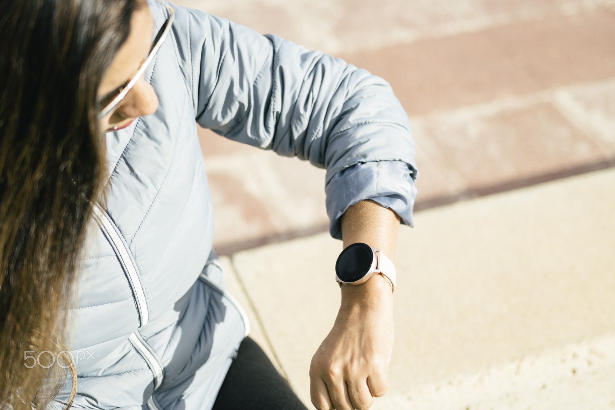 latin woman with long hair looking at smartwatch