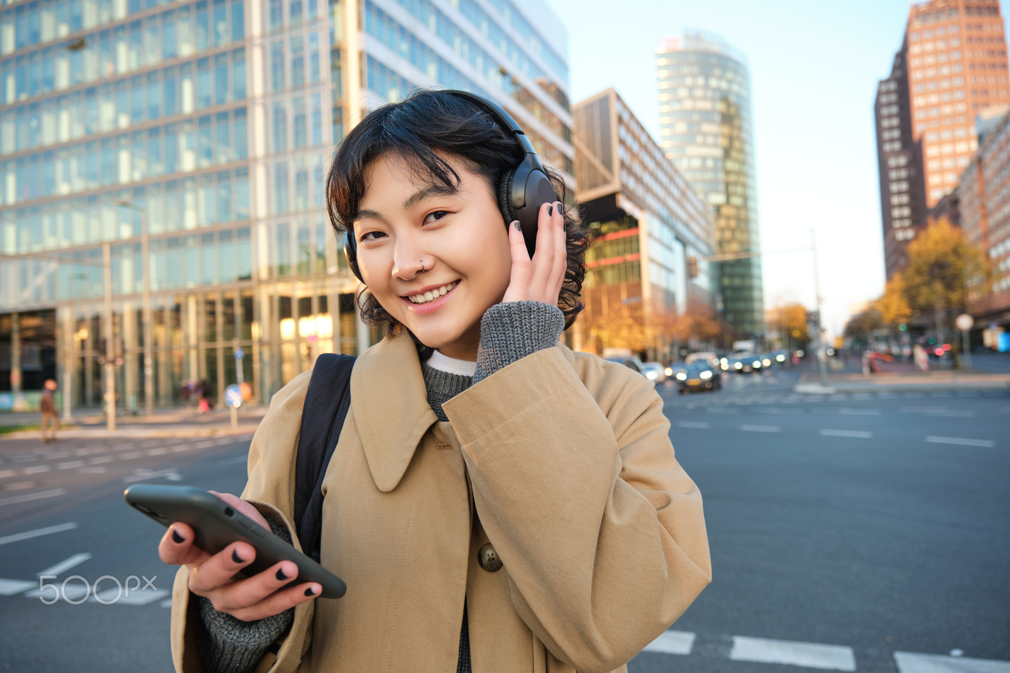Portrait of young asian girl, student walks in city, listens music in