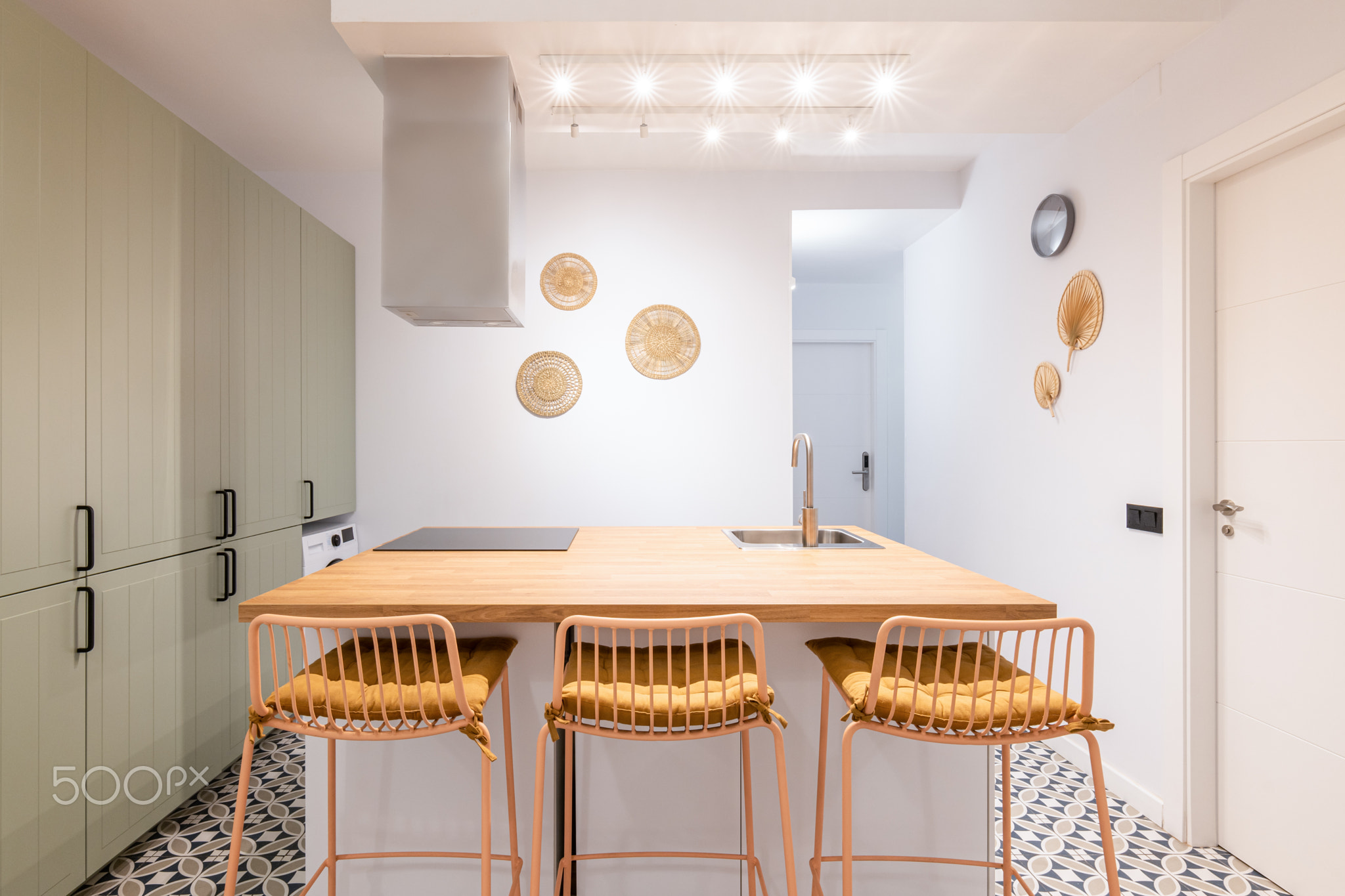 Big kitchen island is surrounded by tall bar stools with soft yellow