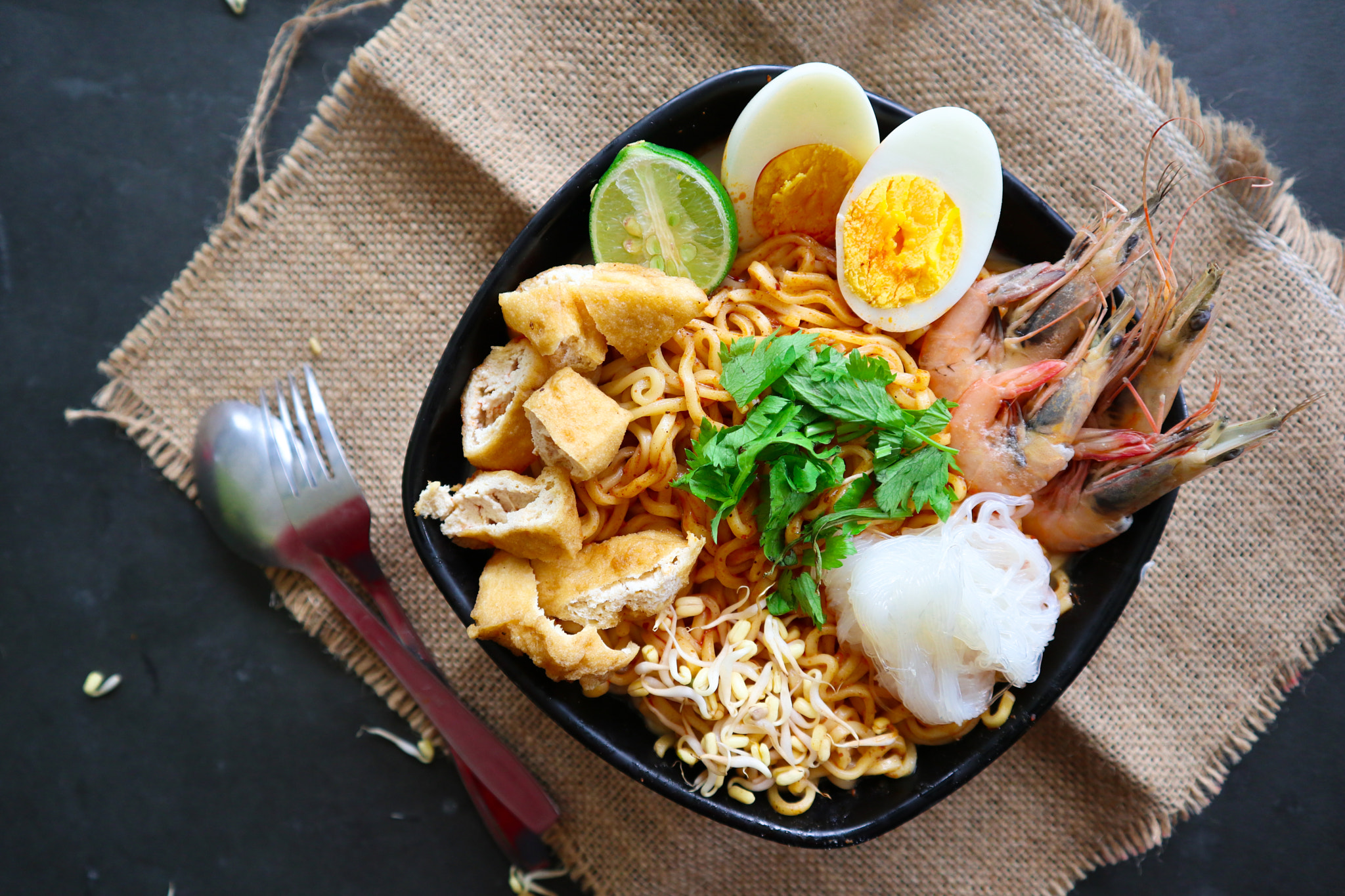 laksa, laksa curry made from vermicelli, noodles, bean sprouts, egg, tofu lime, and shrimp with a sp