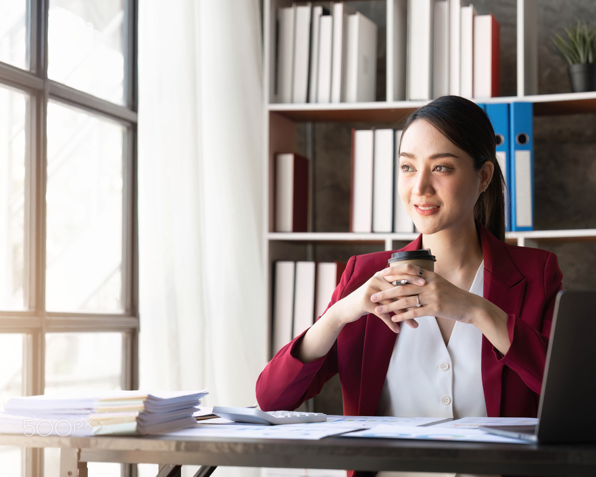 Young Asian american business woman sitting with laptop and cup of