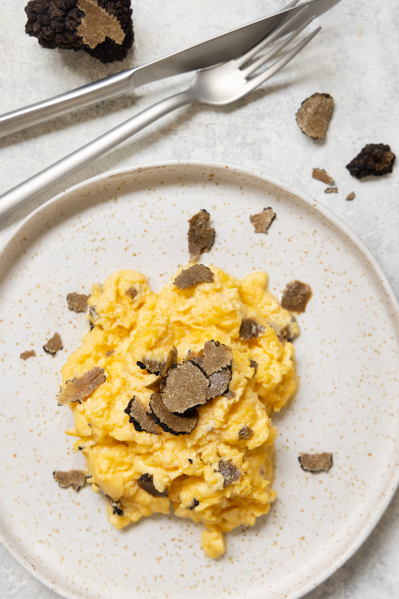 Scrambled eggs with fresh black truffles from Italy served in a plate top view, gourmet breakfast