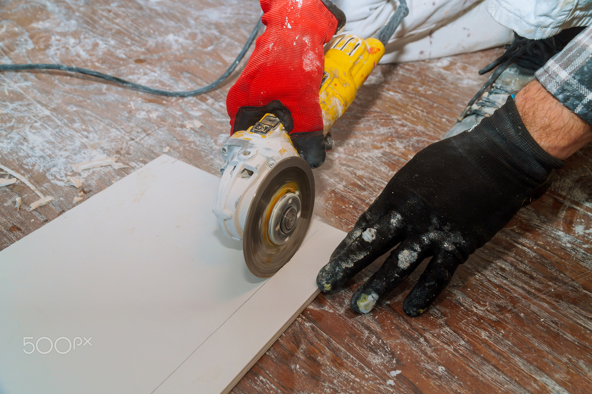 In preparation for laying ceramic tiles on a floor, the tiles are cut