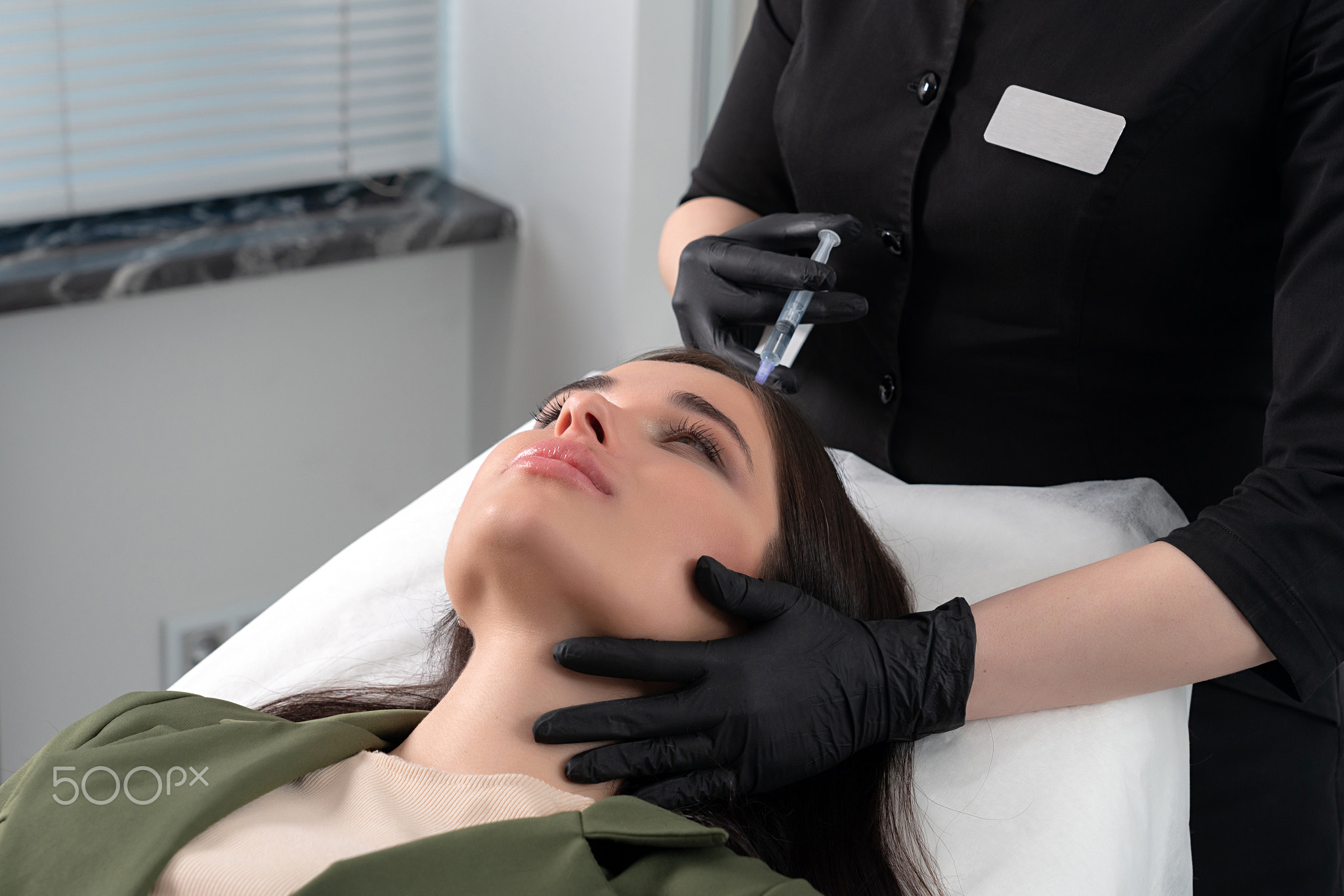 Young woman with hair problem receiving injection in head skin in a