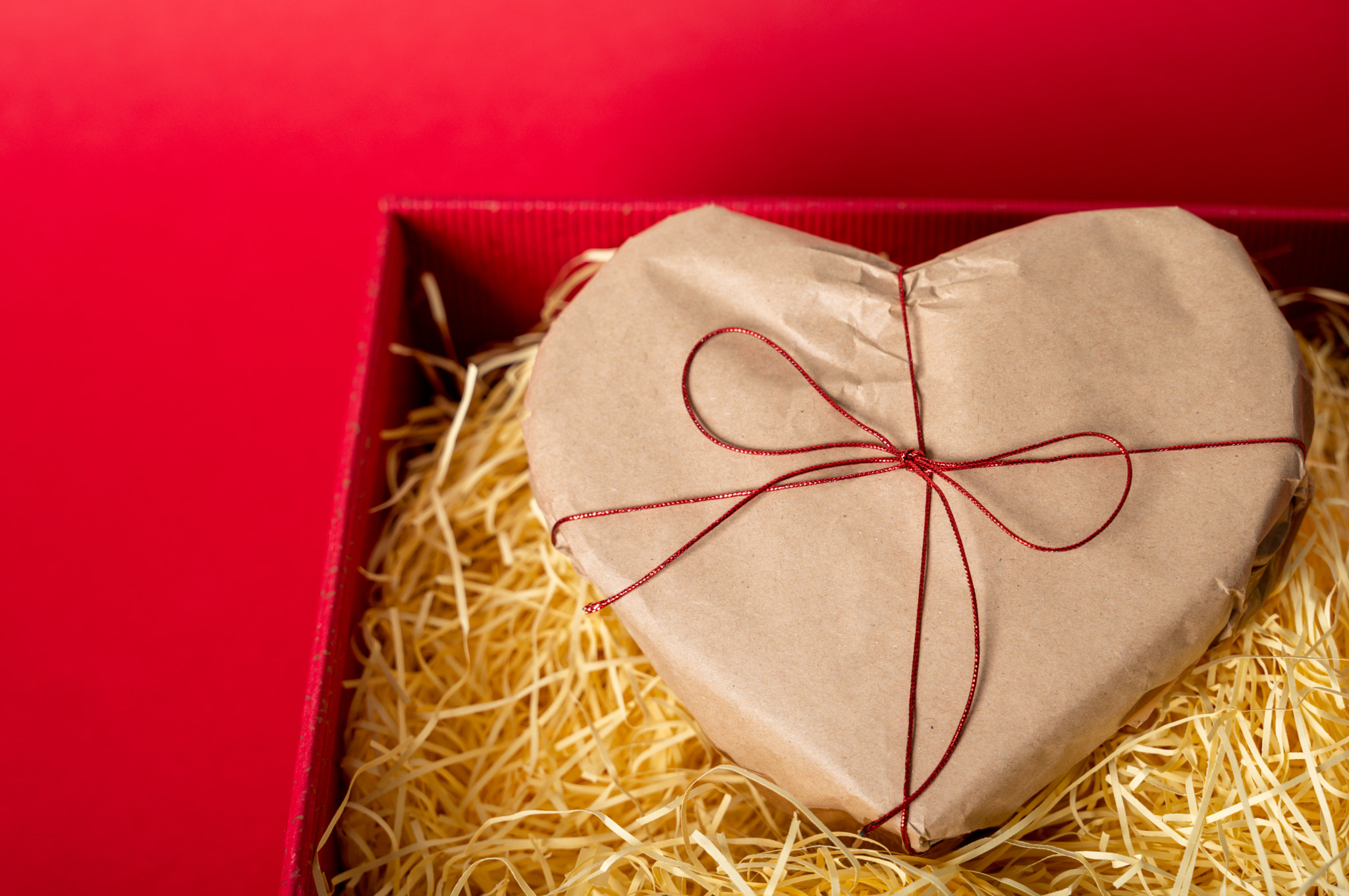 Heart shaped gift in red box with shredder paper