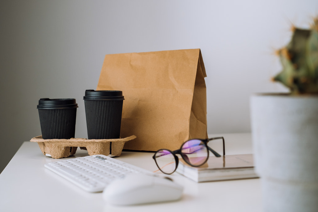 Package with food delivery and cups of coffee at workplace, glasses by Roman Lisovyi on 500px.com