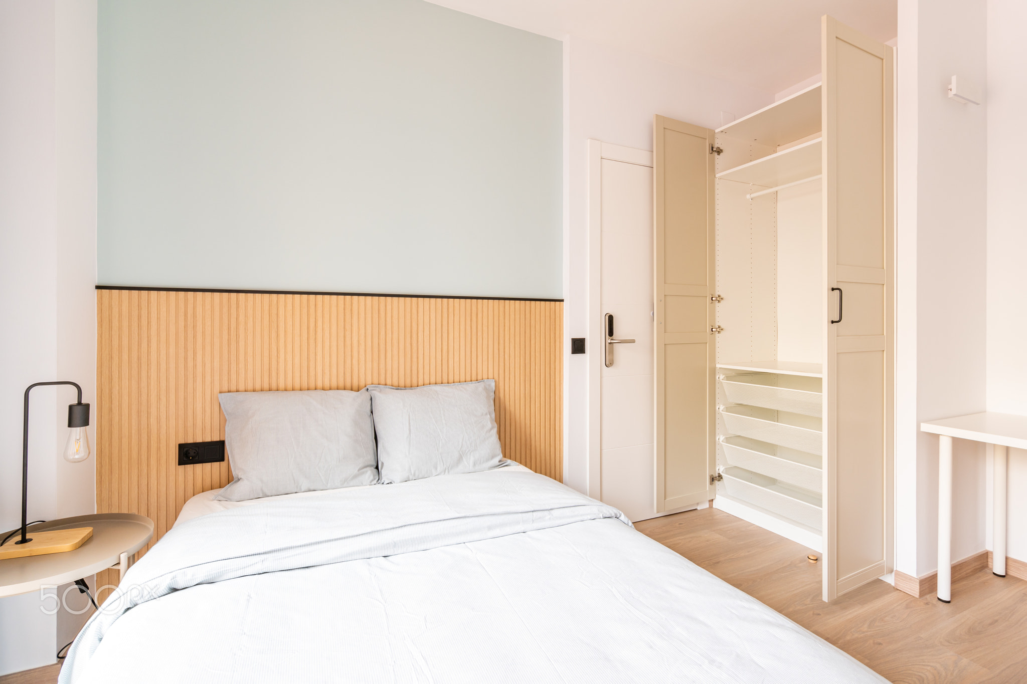 Hotel room with large double bed, beautiful linens. There is wood