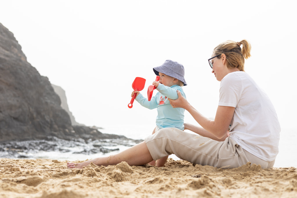 Mother playing his infant baby boy son on sandy beach enjoying summer by Matej Kastelic on 500px.com