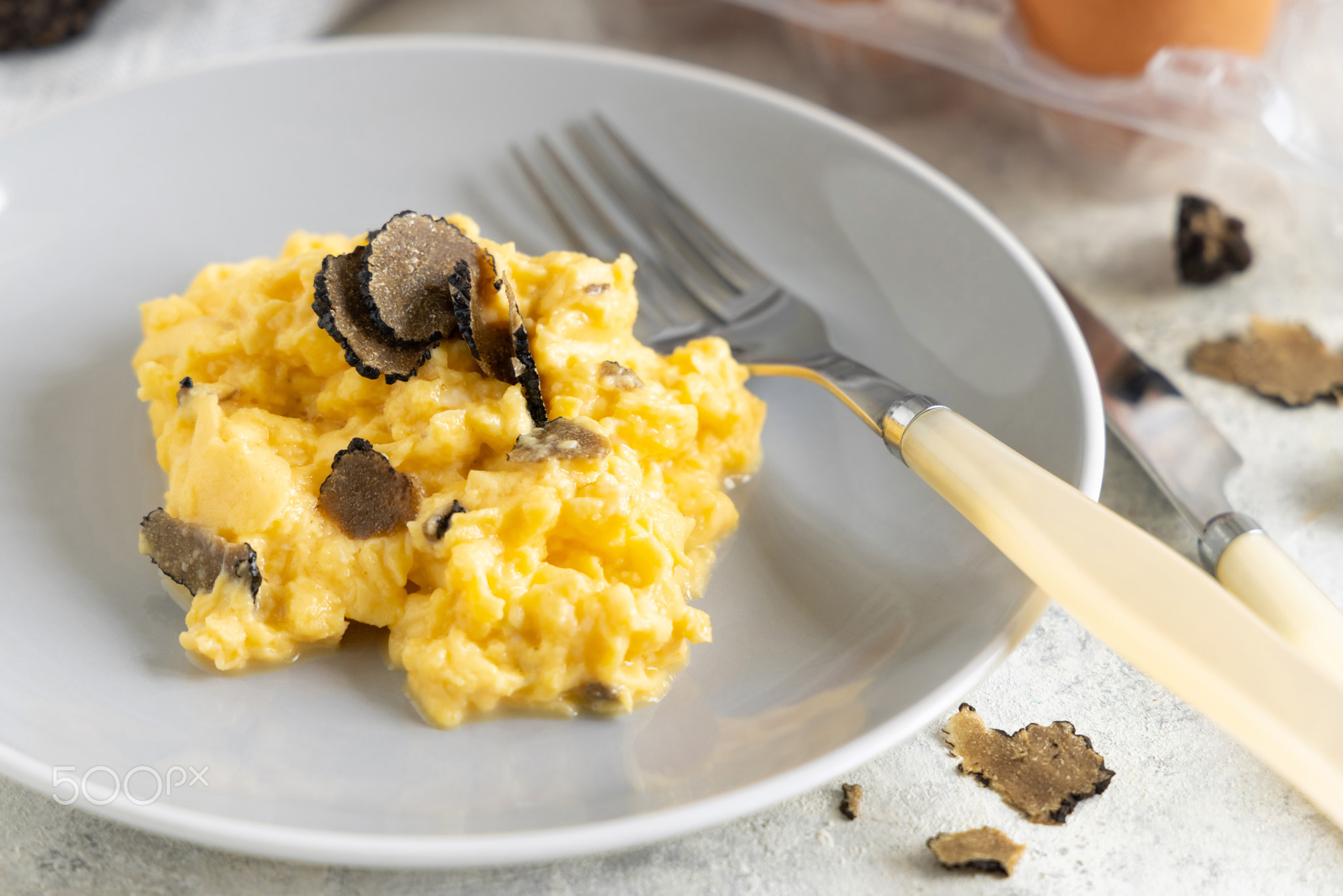 Scrambled eggs with fresh black truffles from Italy served in a plate close up, gourmet breakfast