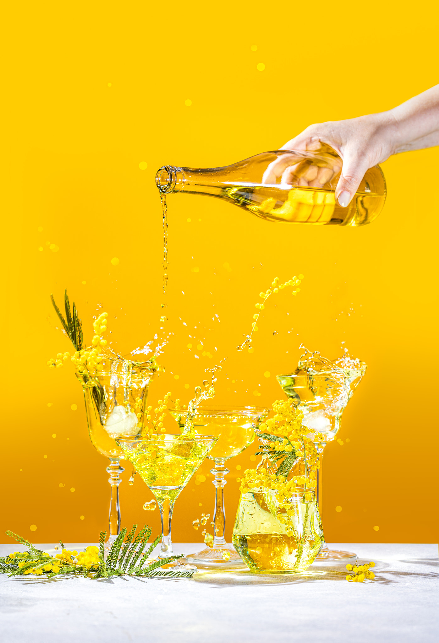 Various elegant martini and whiskey glasses with sparkling water, womans hand pouring water