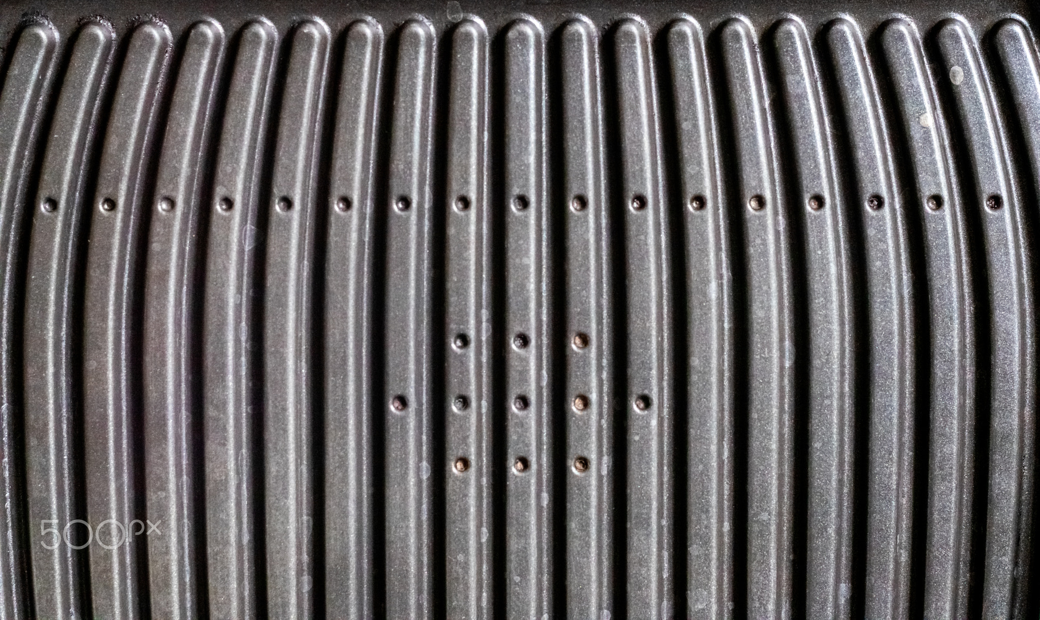 Black electric grill grate, textured background. The surface of the